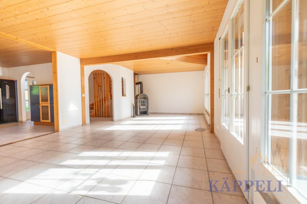 Großer heller Wohnraum mit Holzdecke und Kaminofen