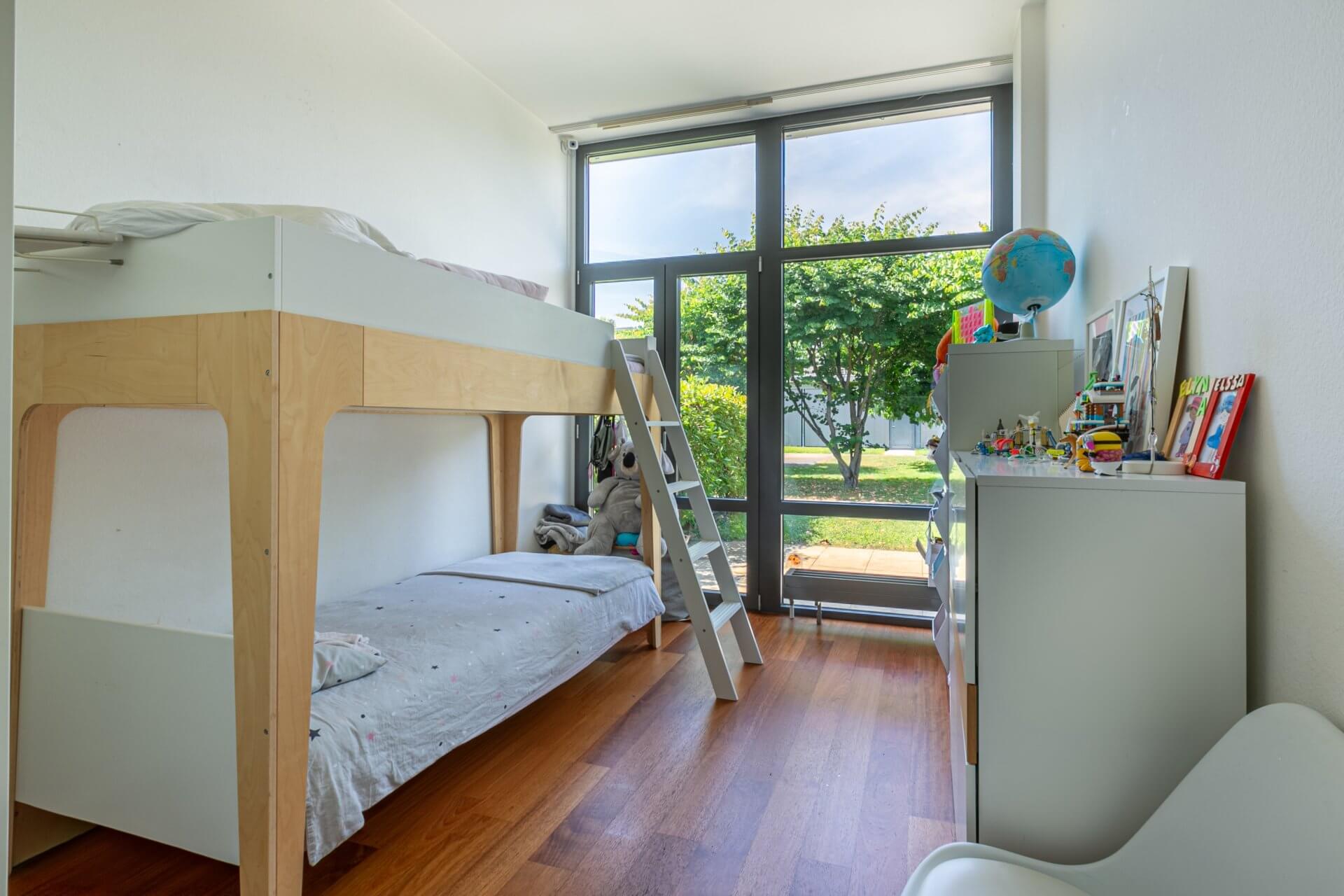 Kinderzimmer mit Hochbett und großem Fenster