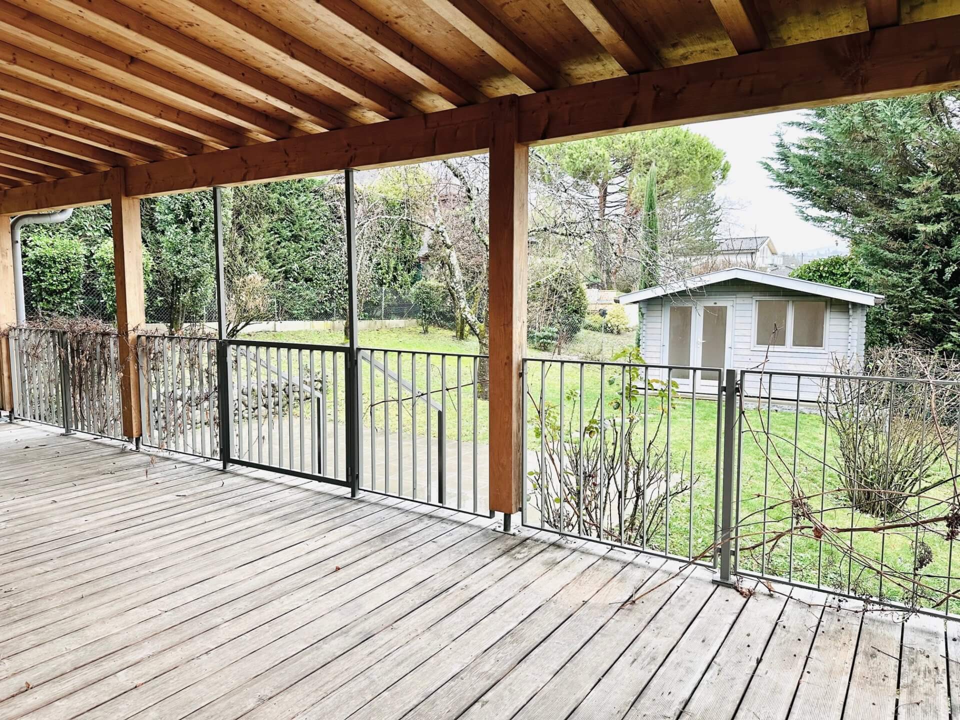 Überdachte Holzterrasse mit Gartenblick