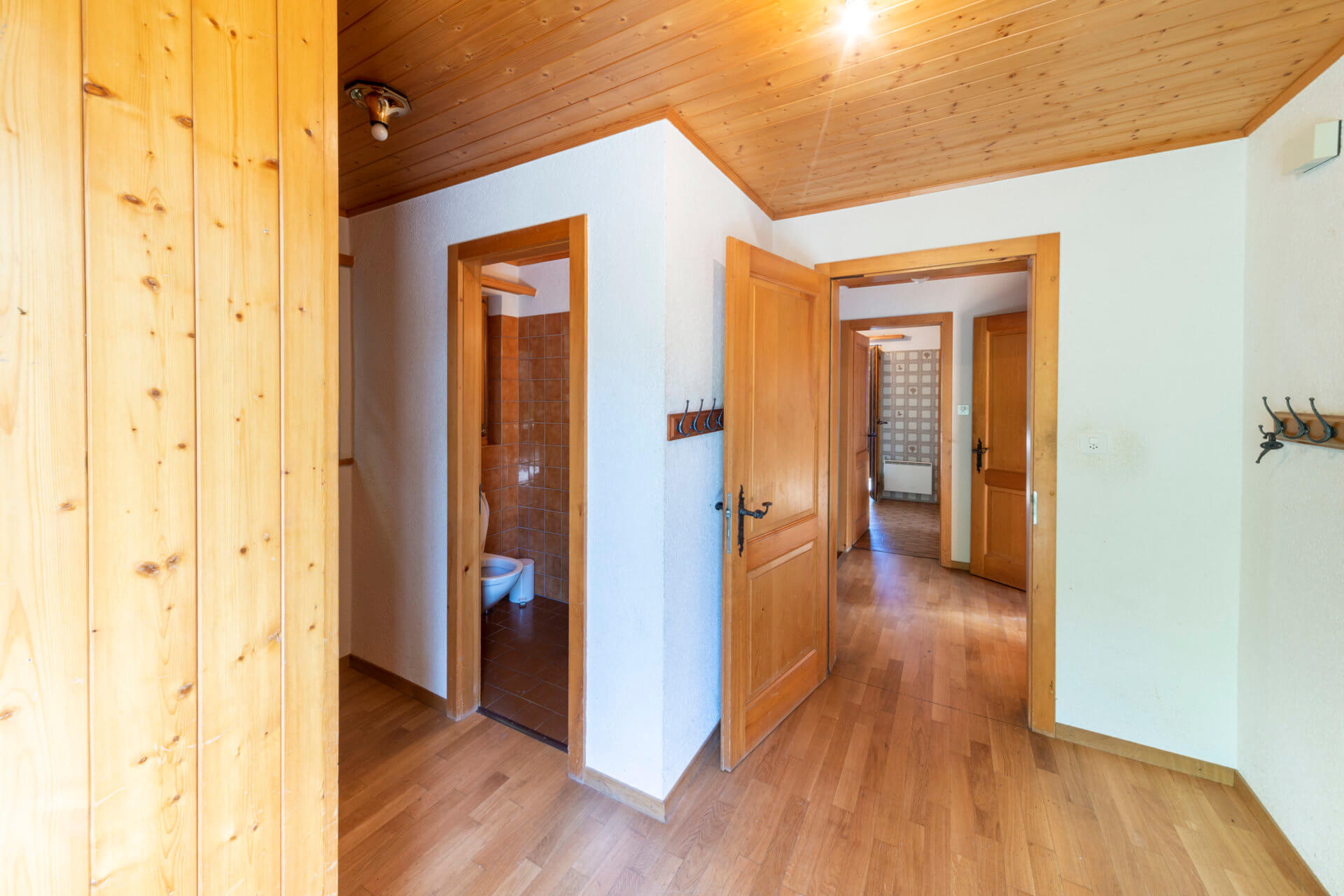 Heller Flur mit Holzverkleidung und angrenzendem Bad
