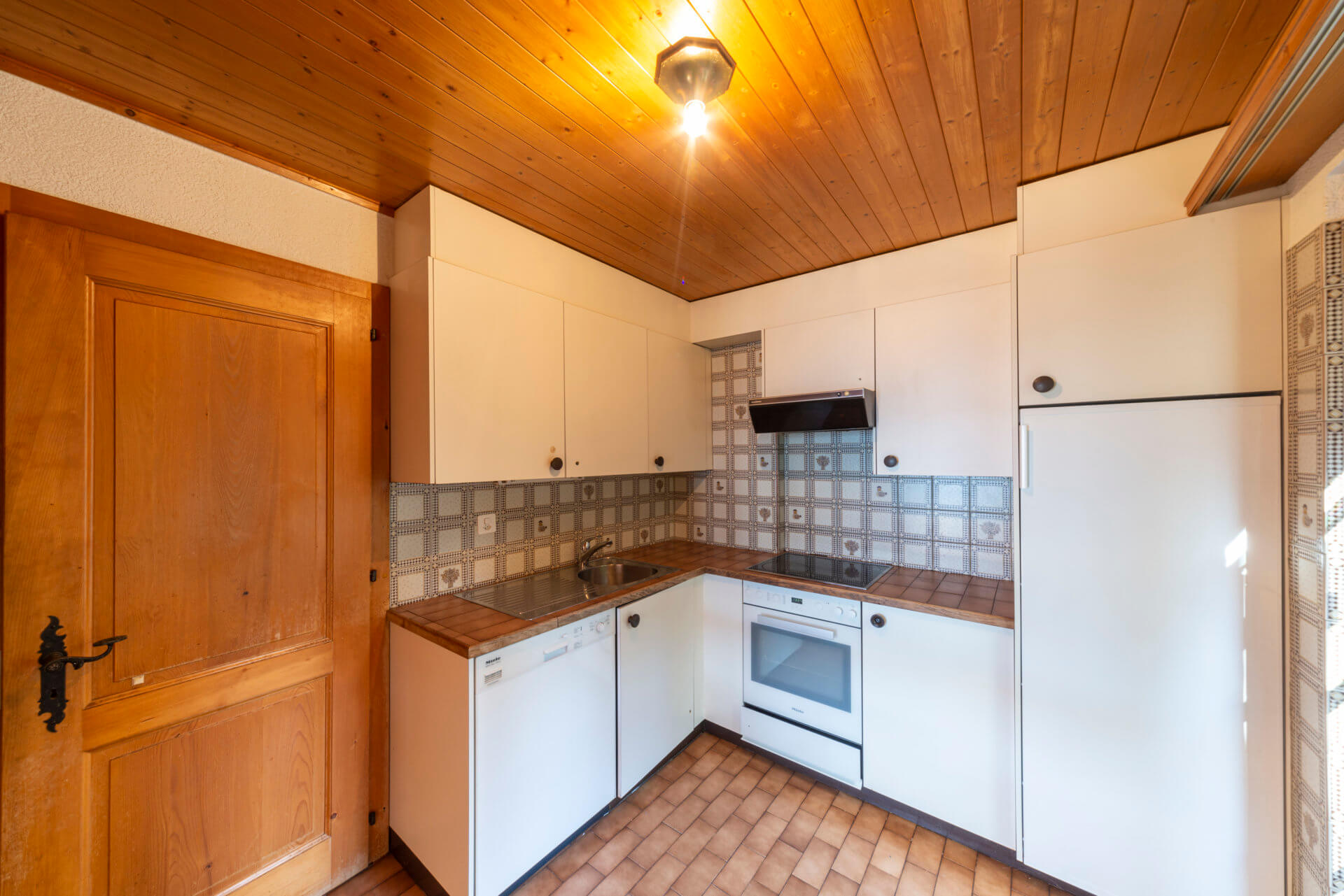 Kleine Küche mit Holzdecke und Fliesenboden