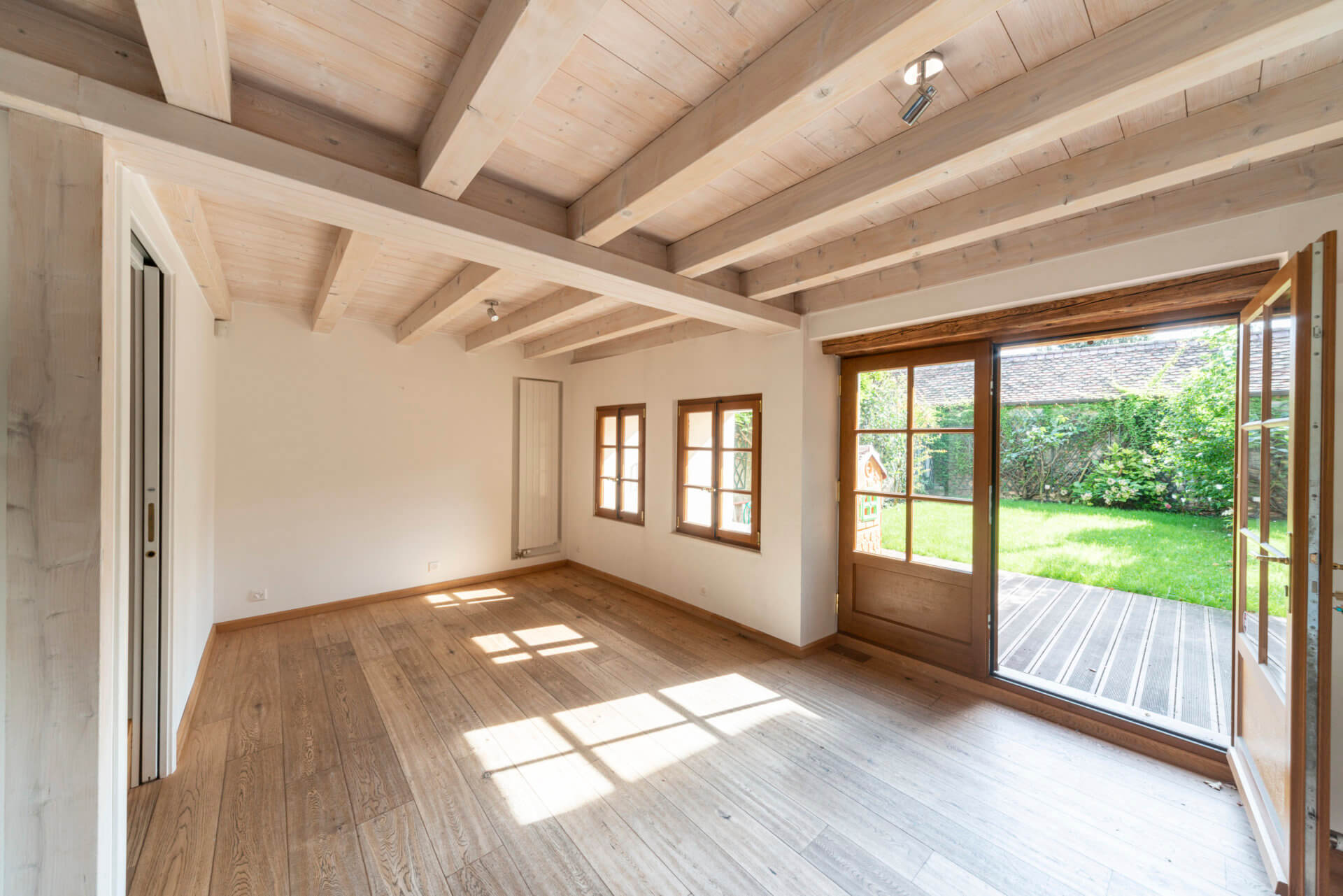 Heller Wohnraum mit Holzbalkendecke und Gartenausgang