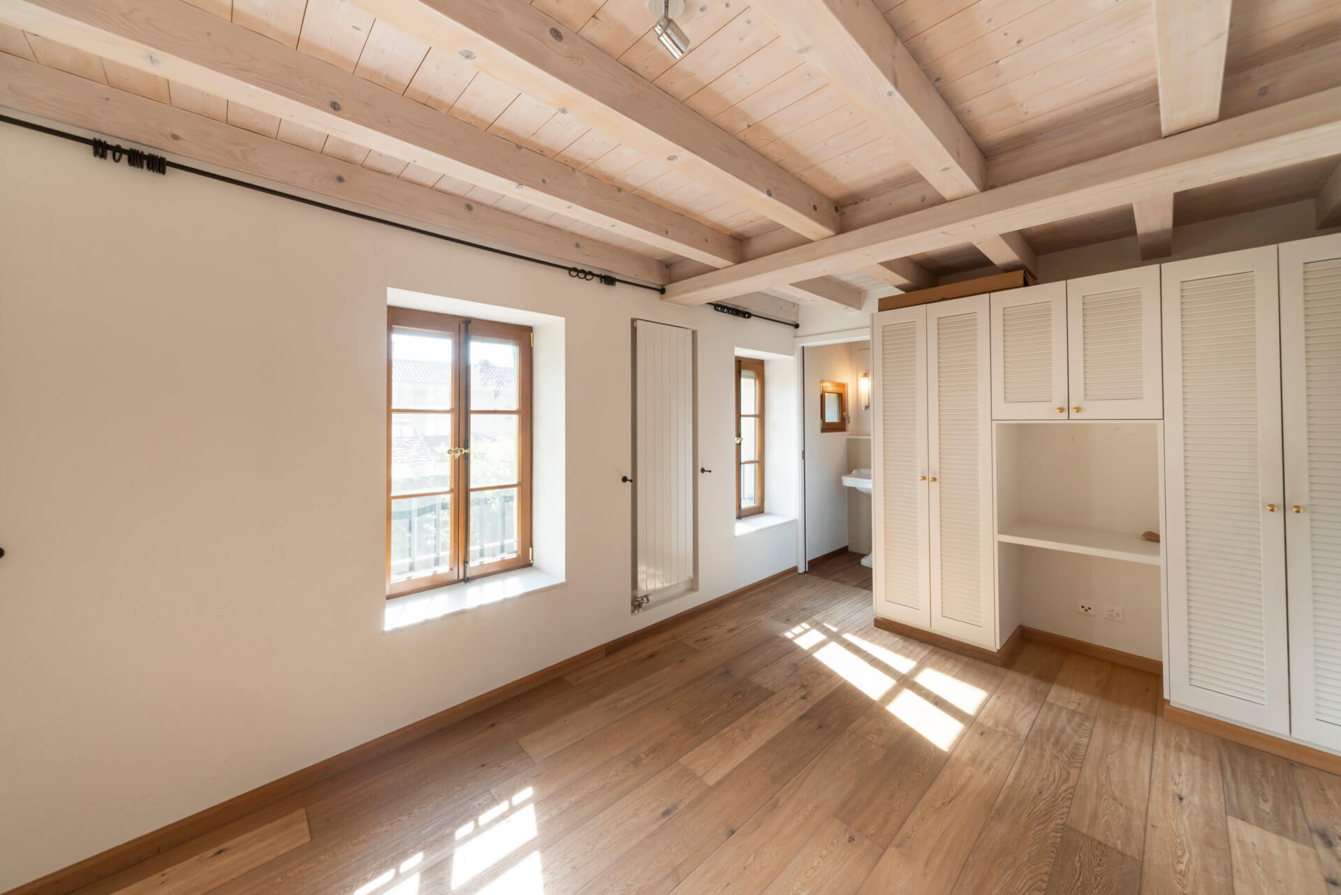 Heller Raum mit Holzbalkendecke und Einbauschrank