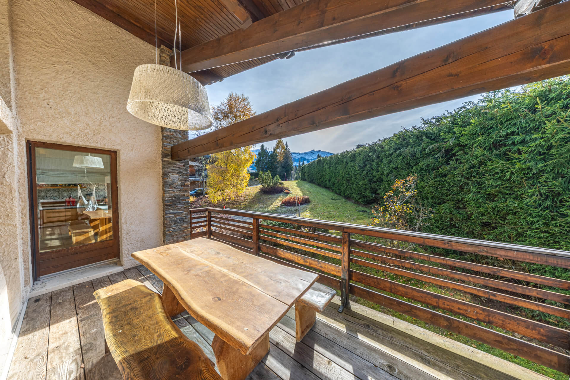 Überdachte Holzterrasse mit Berg- und Gartenblick