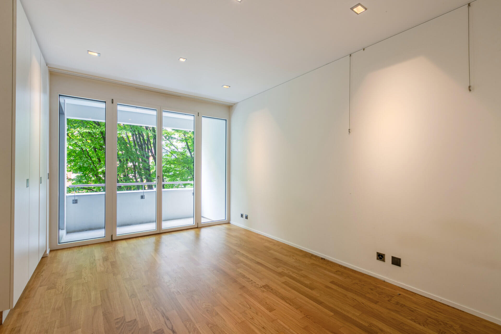 Leerer heller Raum mit Balkon und Parkett