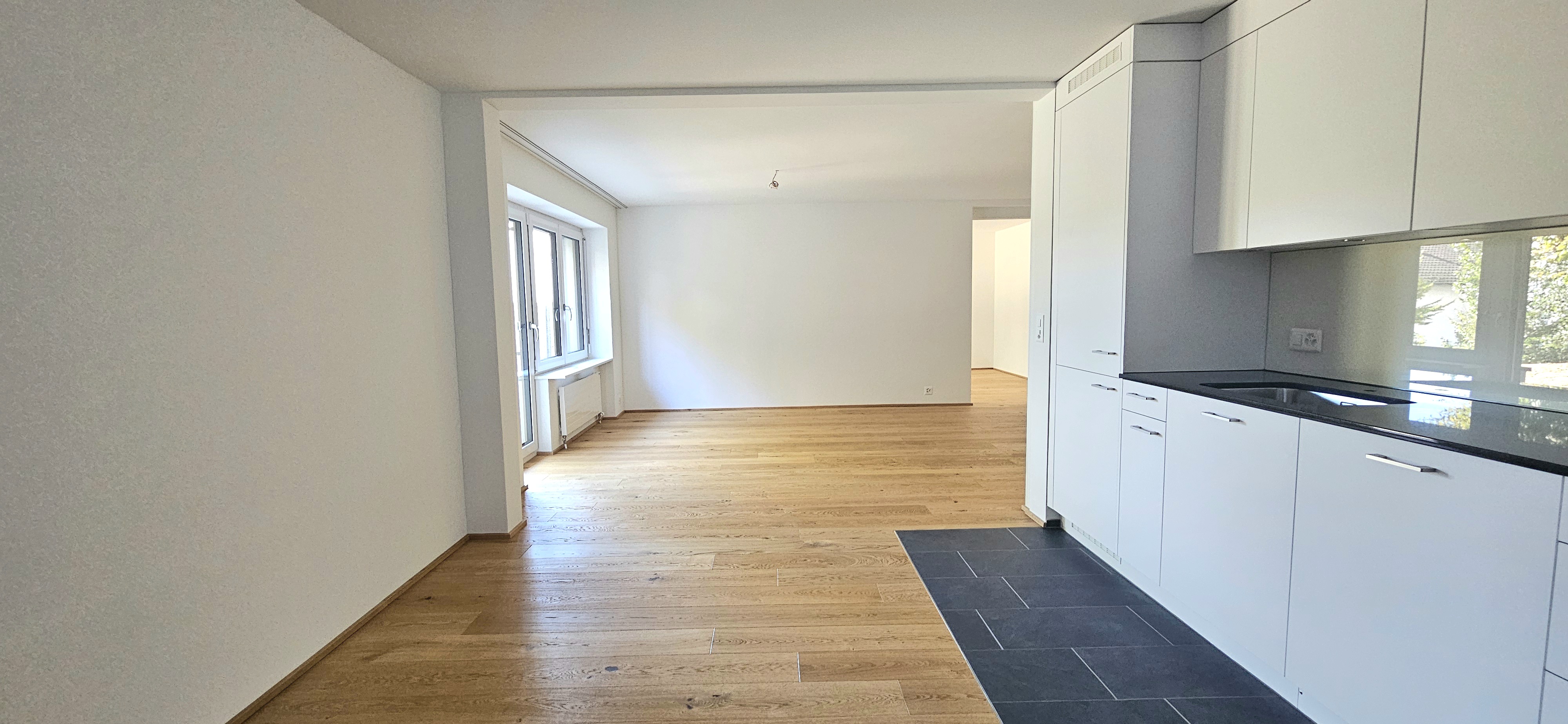 Helle, leer wirkende Wohnküche mit offener Raumwirkung