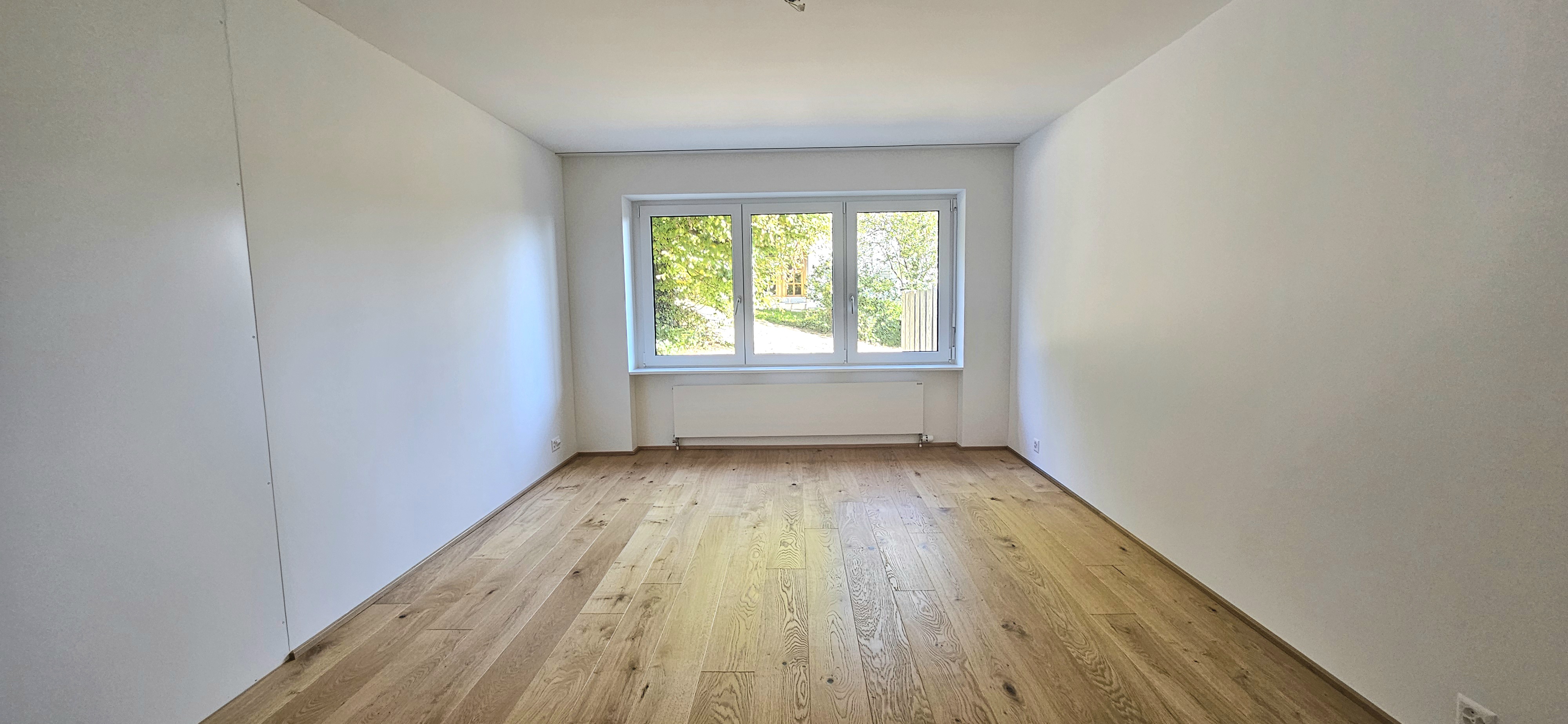 Leerer heller Raum mit Holzboden und Fenster
