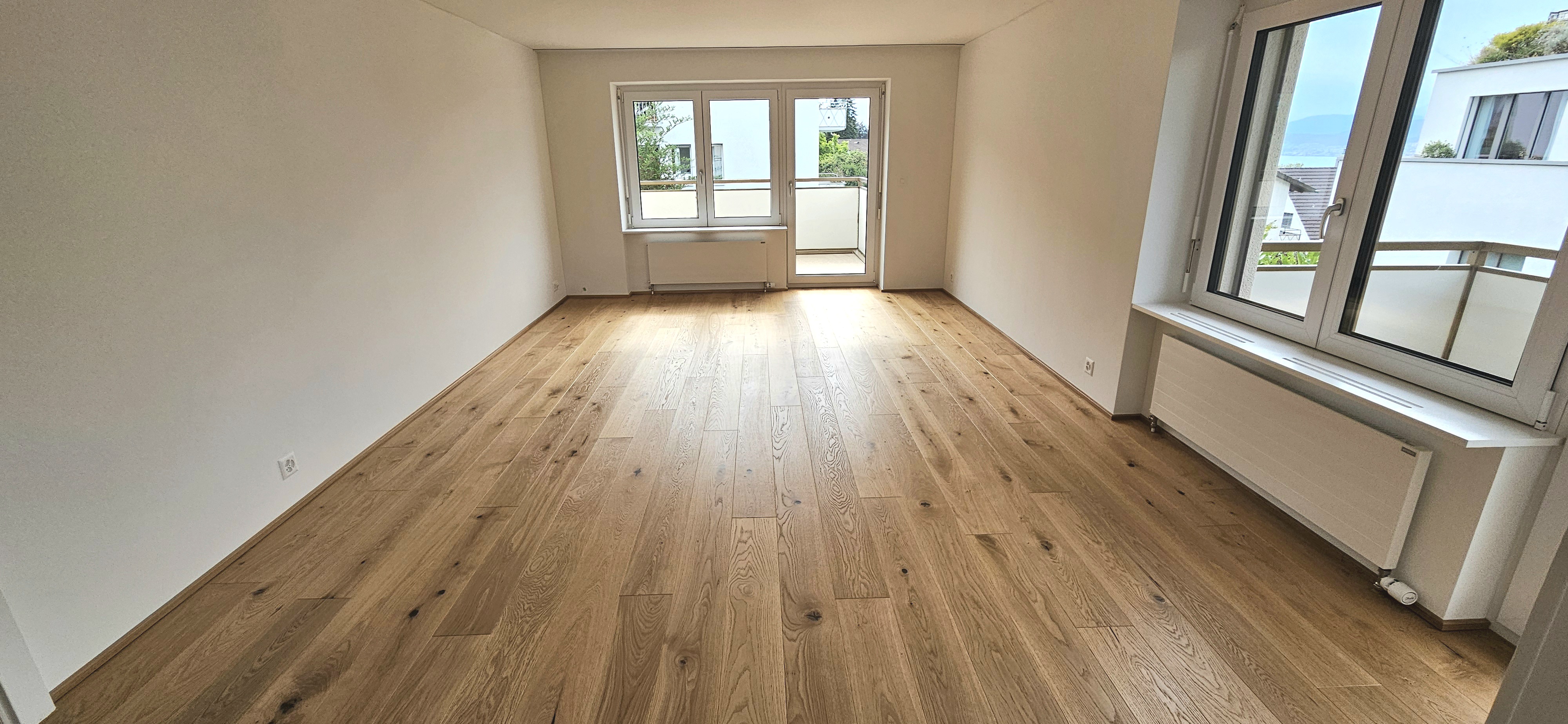 Heller leerer Wohnraum mit Parkett und Balkon