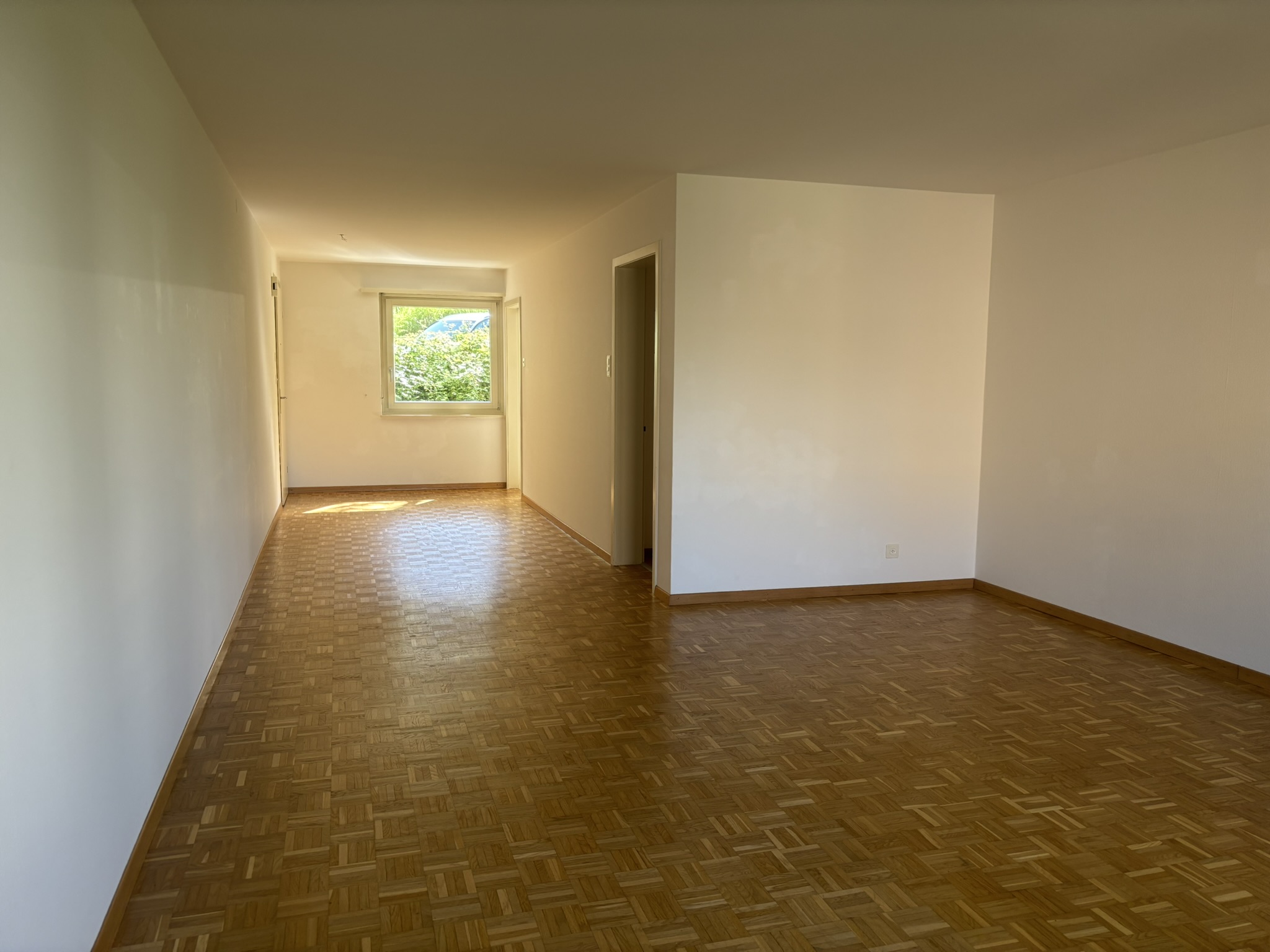 Leerer Wohnraum mit Parkett und Fenster