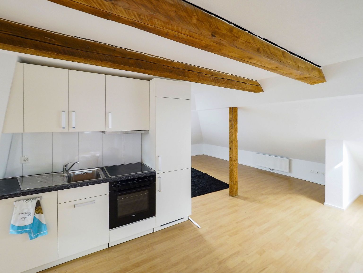 Offene Dachgeschossküche mit sichtbaren Holzbalken