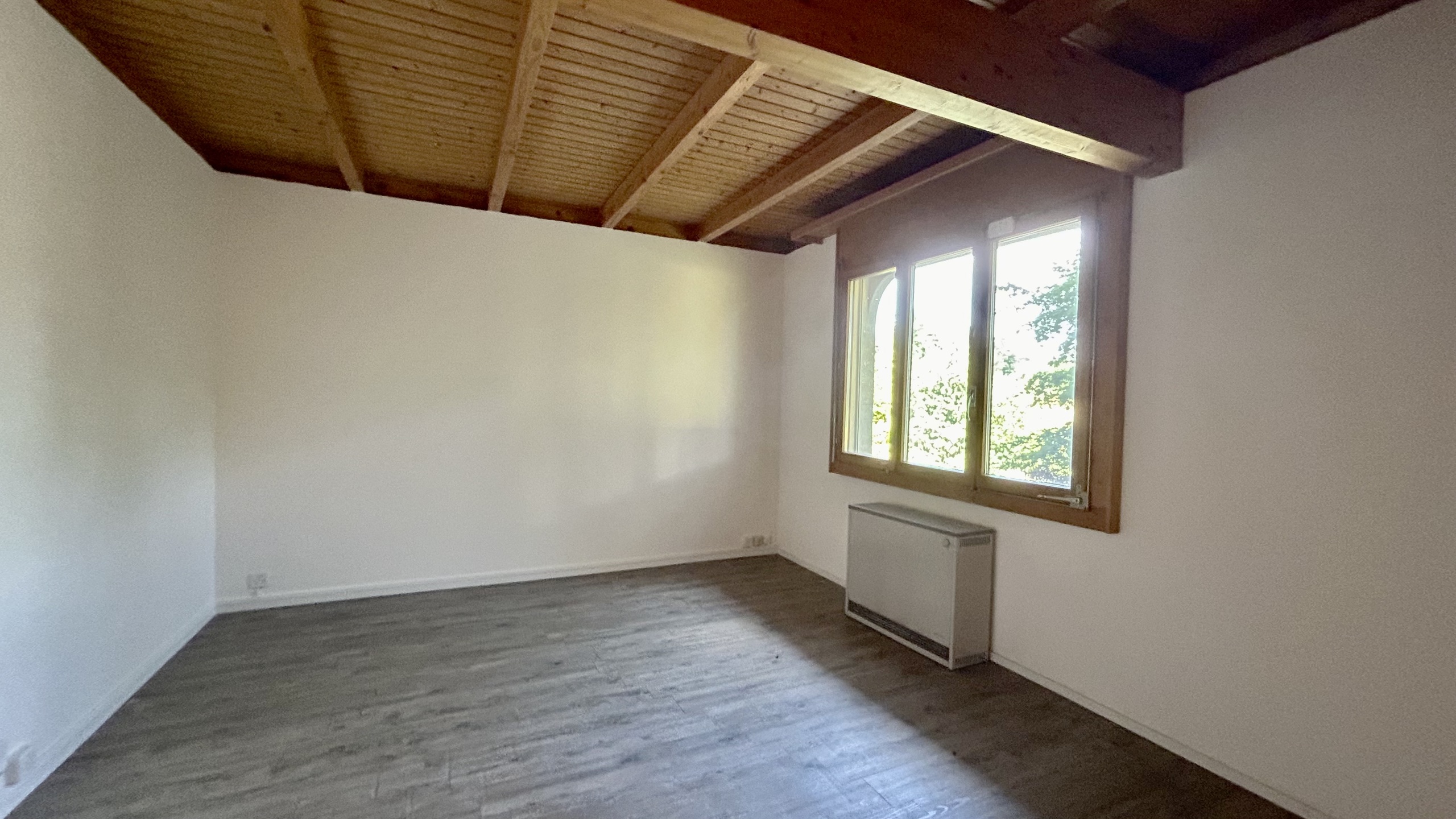 Leerer Raum mit Holzbalkendecke und Fenster