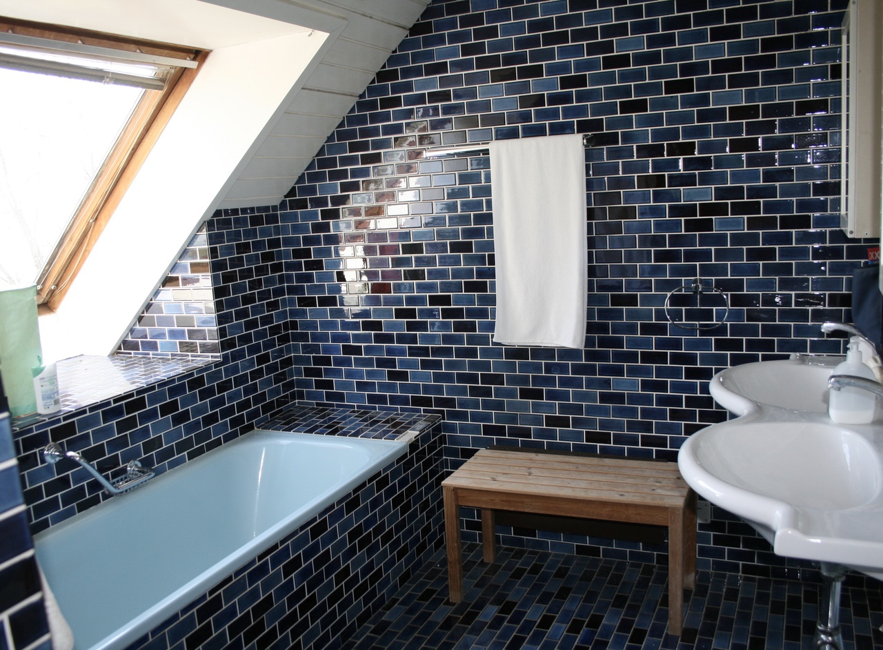 Badezimmer mit blau gefliesten Wänden und Dachfenster