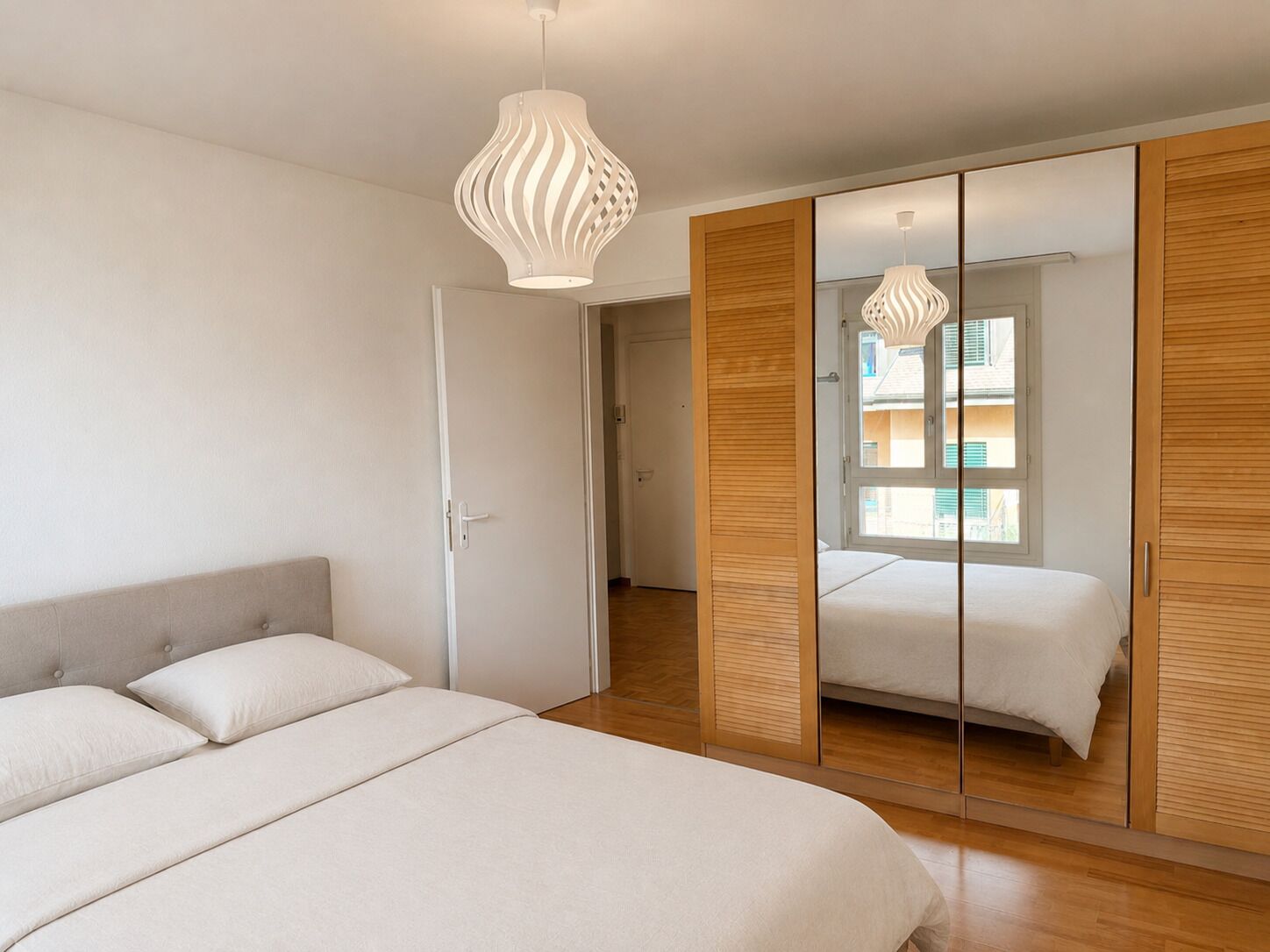 Helles Schlafzimmer mit Einbauschrank und Fensterblick