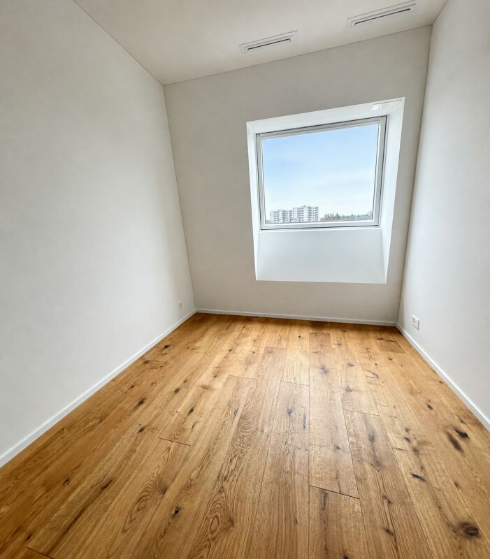 Leerer heller Raum mit Fenster und Holzboden
