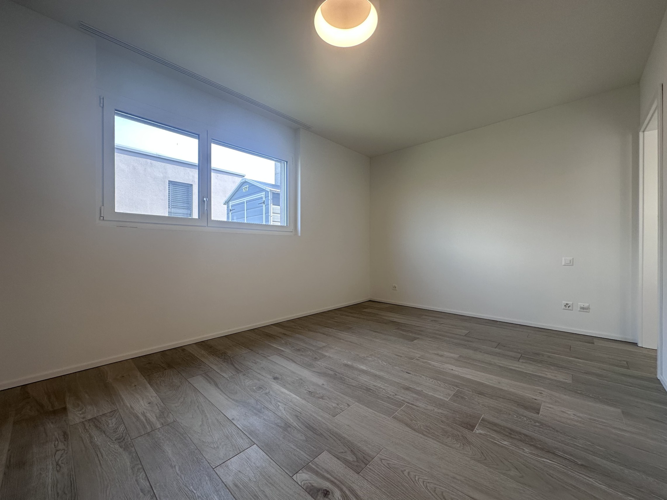 Leerer, neu wirkender Wohnraum mit Holzoptikboden