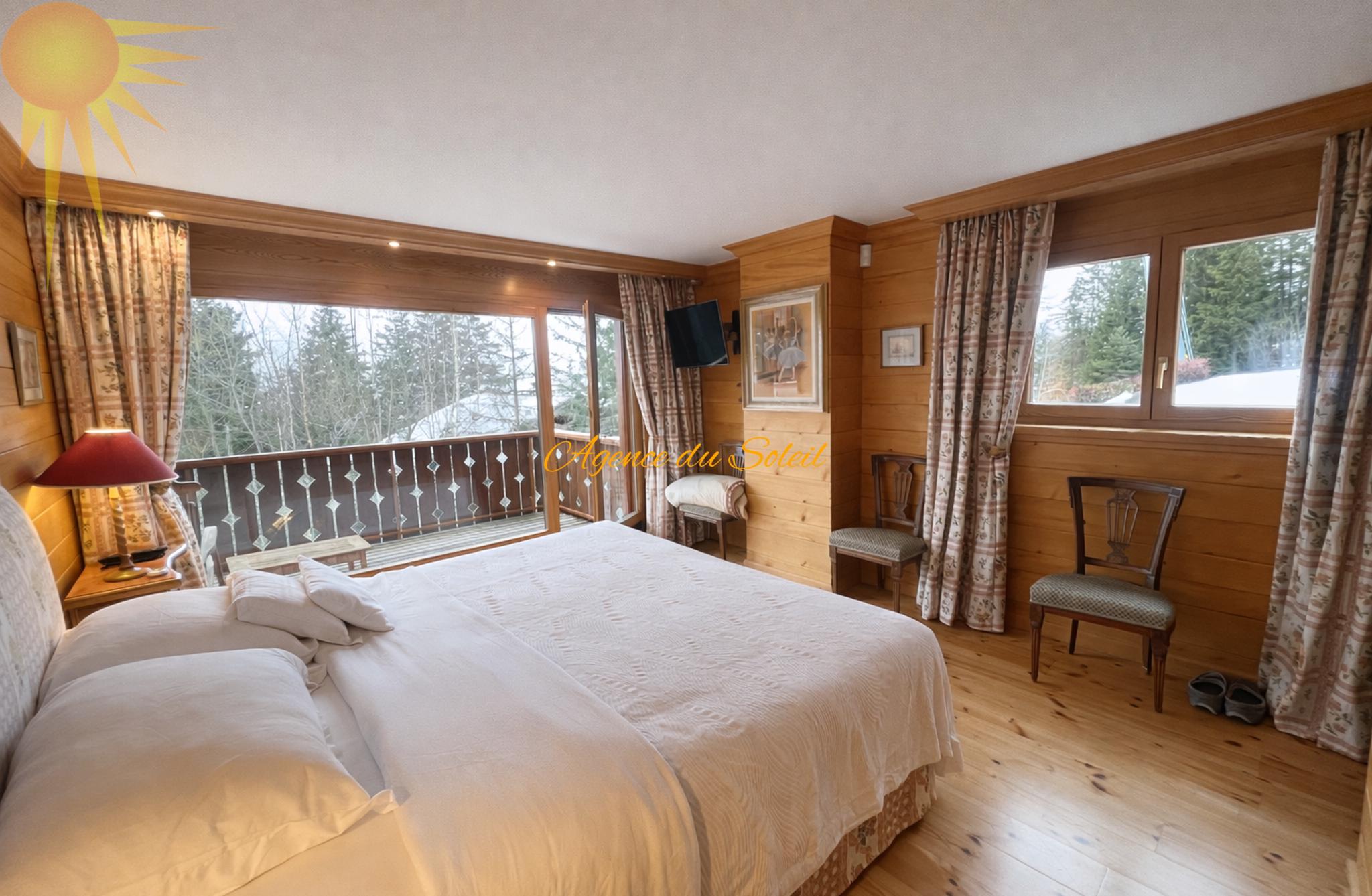 Gemütliches Schlafzimmer mit Holzvertäfelung und Balkonblick