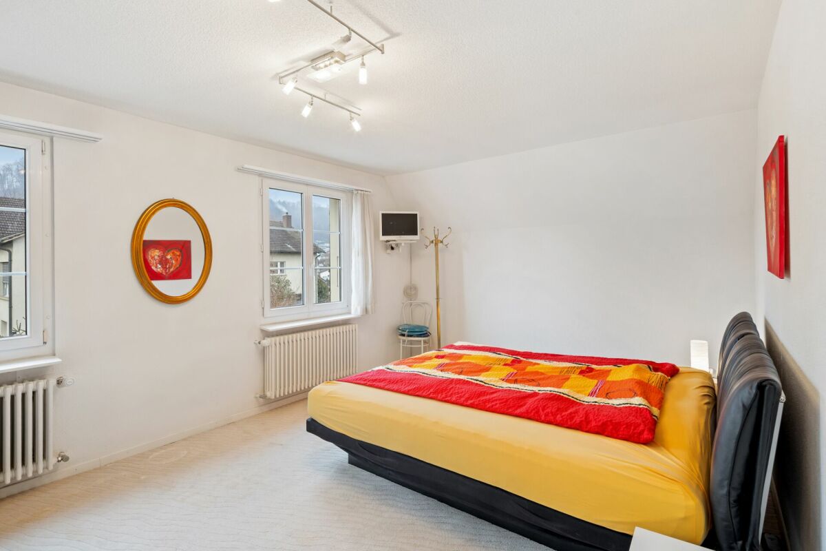 Helles Schlafzimmer mit Doppelbett und Blick auf die Nachbarschaft