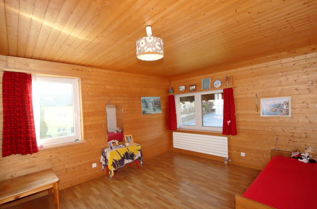 Holzverkleidetes Zimmer mit roten Vorhängen