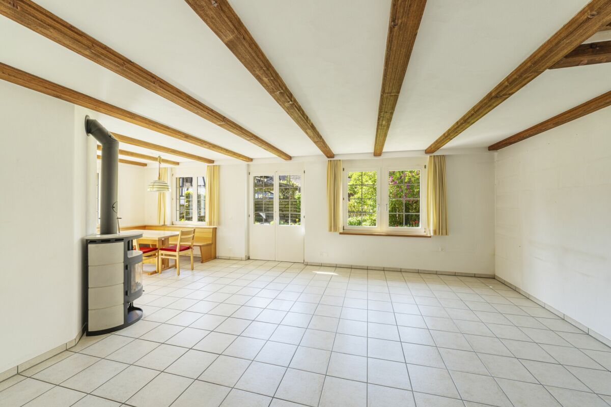 Heller Wohnraum mit Holzdeckenbalken und Kaminofen