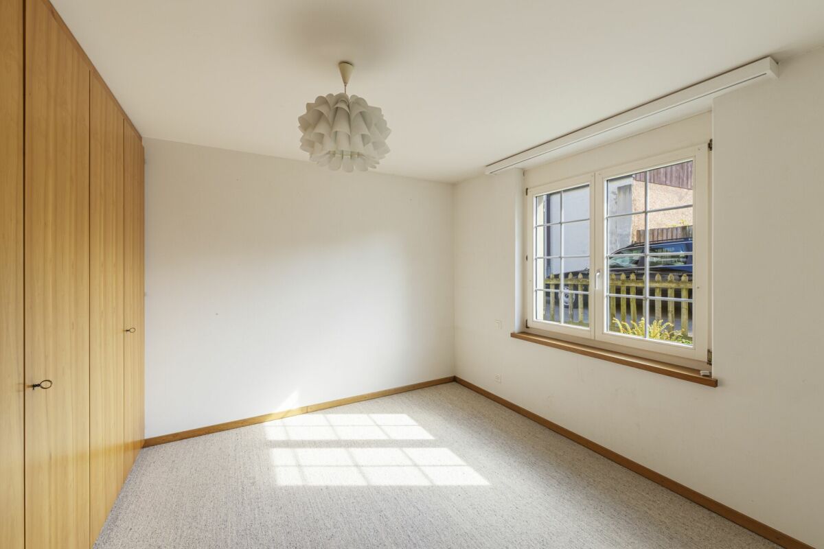 Helles, leeres Schlafzimmer mit Einbauschrank und Fenster