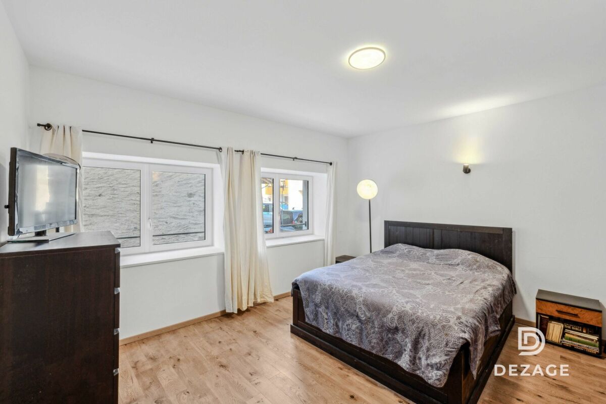 Schlafzimmer mit Doppelbett und zwei Fenstern