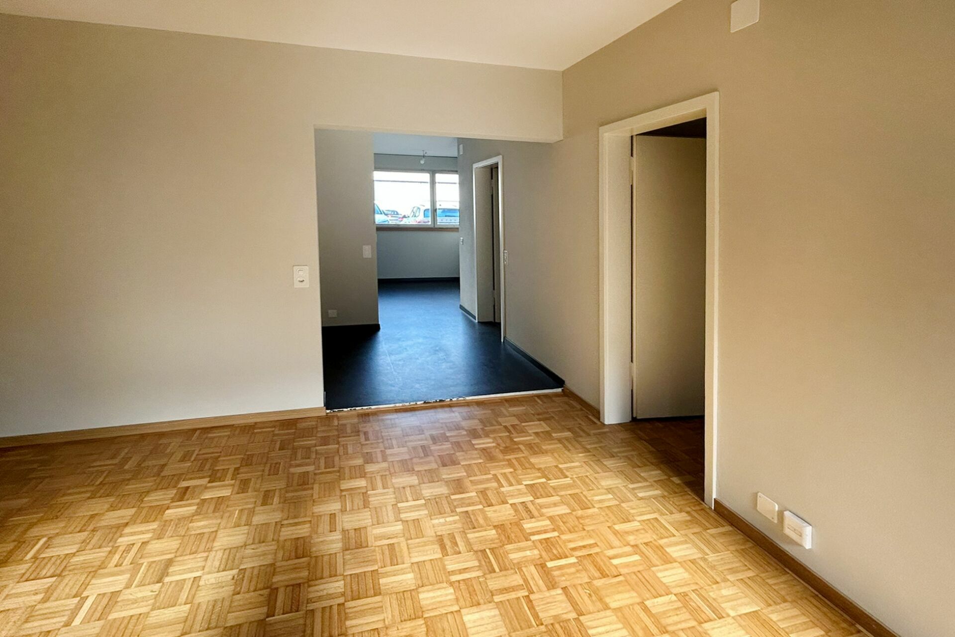 Leerer Wohnraum mit Parkett und Durchgang