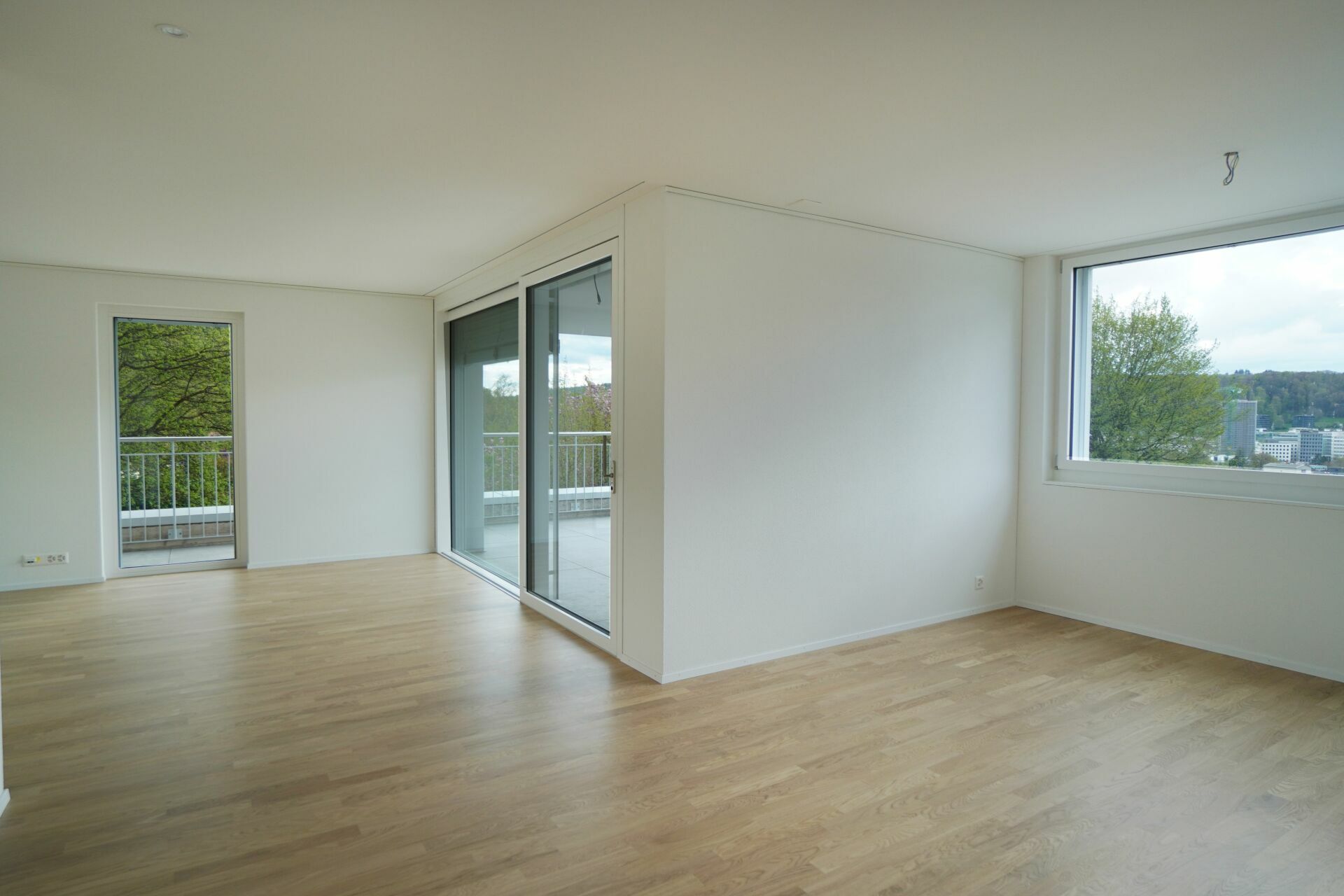 Leerer Wohnraum mit Balkon und großem Fenster
