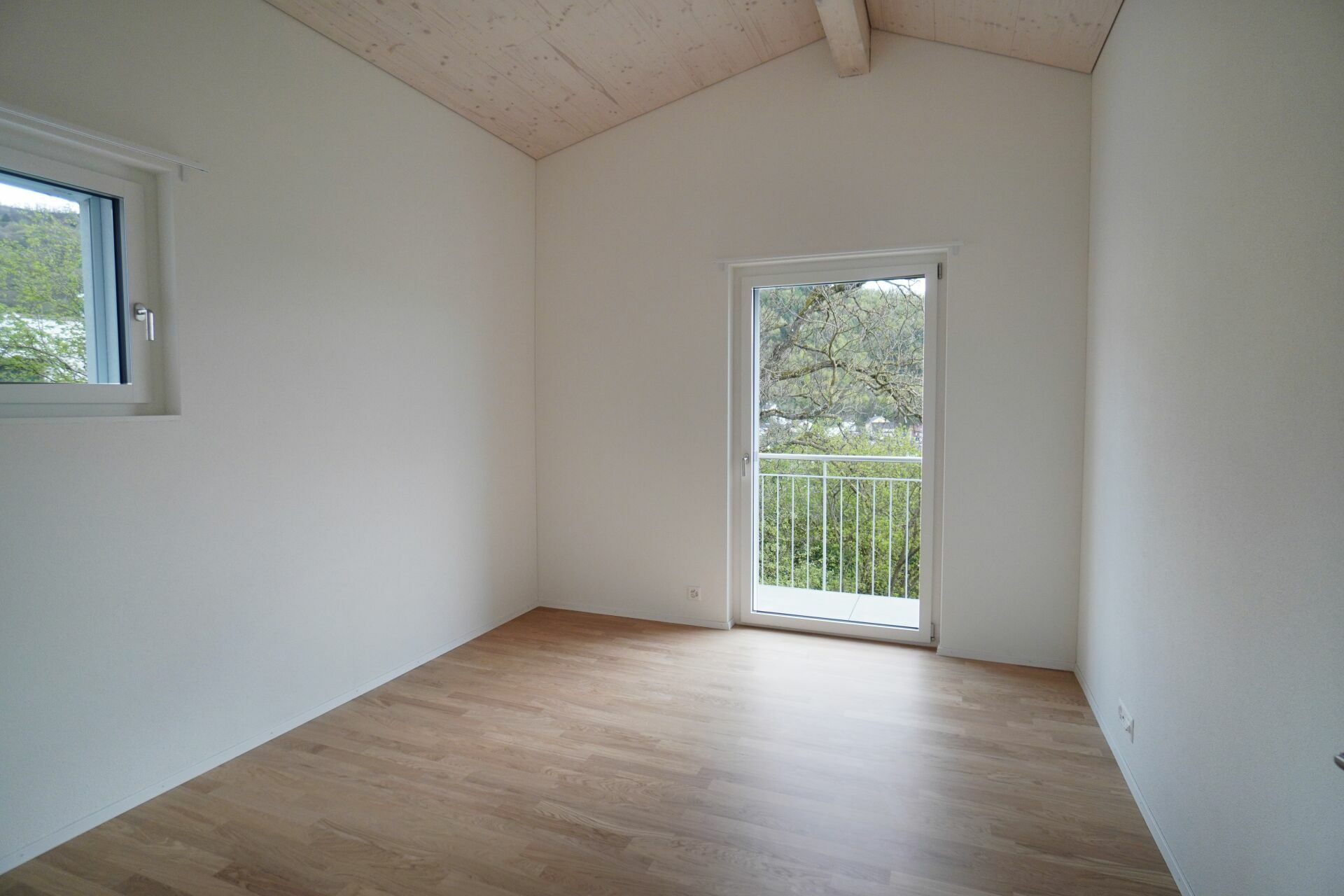 Heller leerer Raum mit Balkon und Holzboden