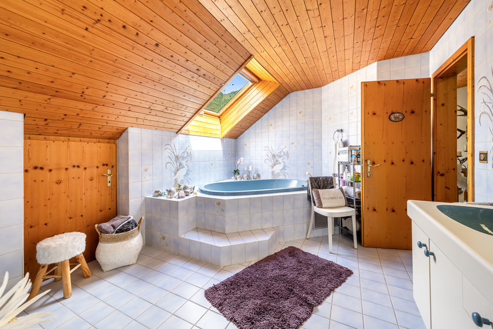 Badezimmer mit Holzdecke und Eckbadewanne