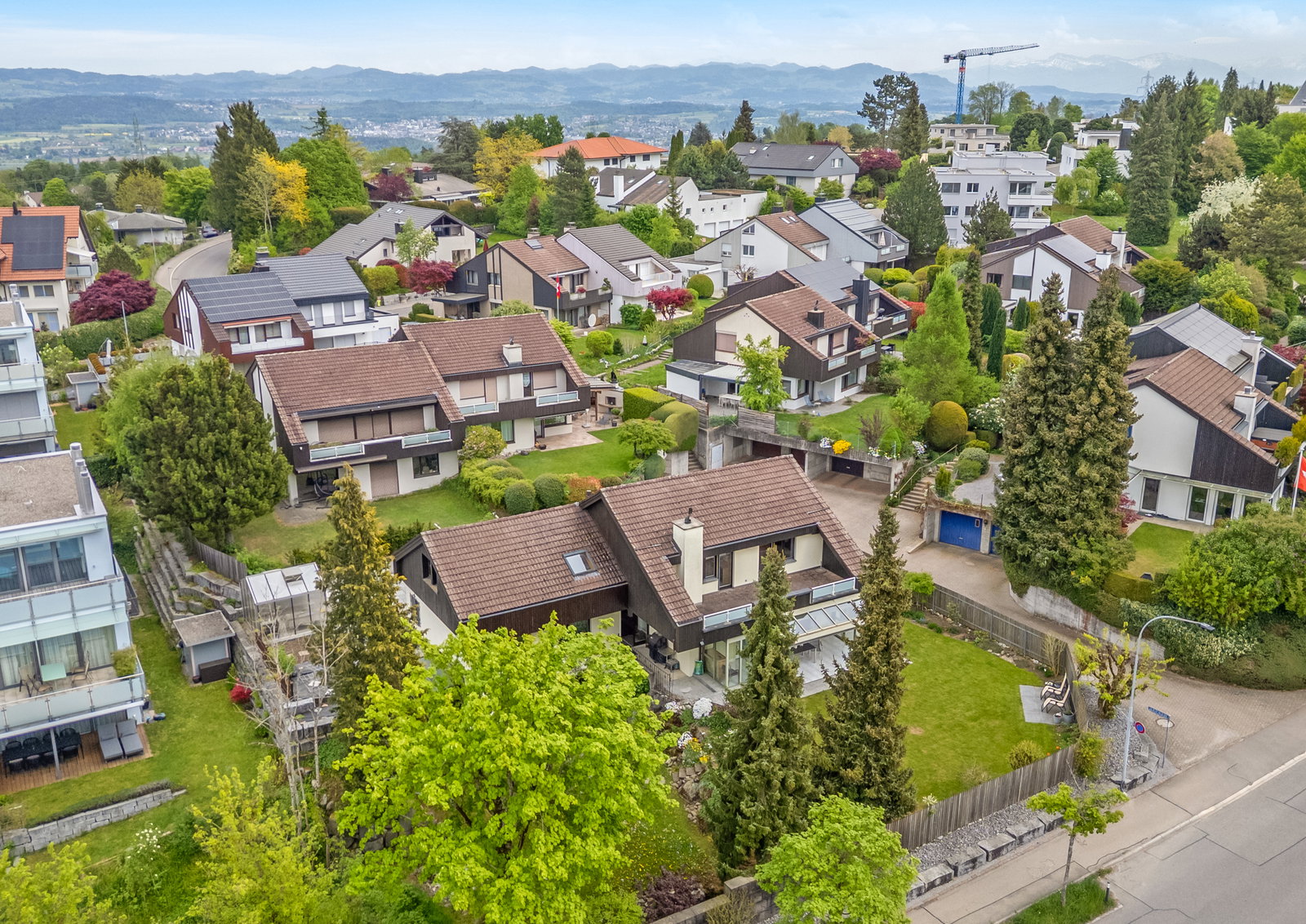 Luftaufnahme einer Wohnsiedlung mit Einfamilienhäusern und Bergpanorama