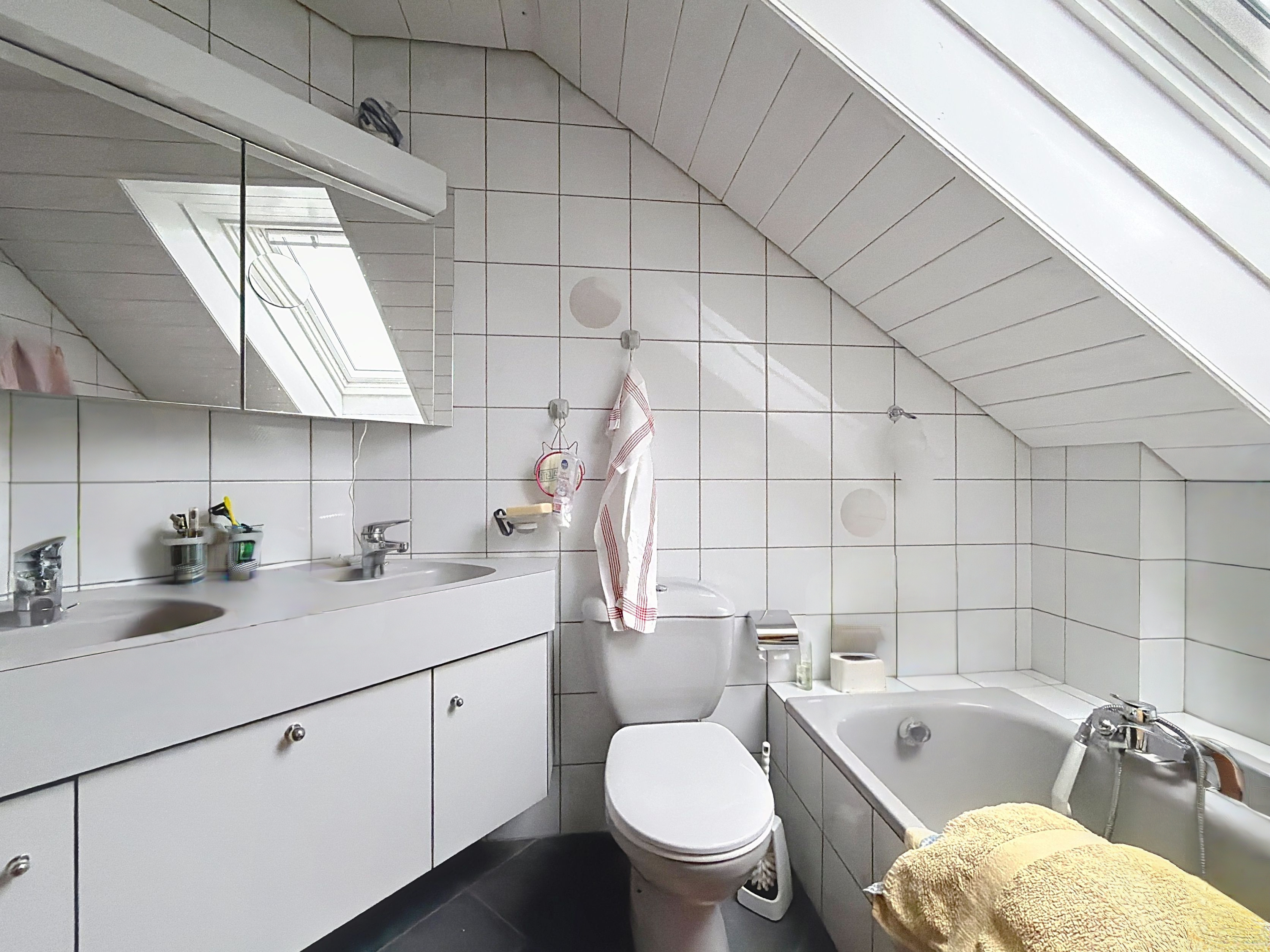 Kleines Dachgeschoss-Badezimmer mit Badewanne und WC