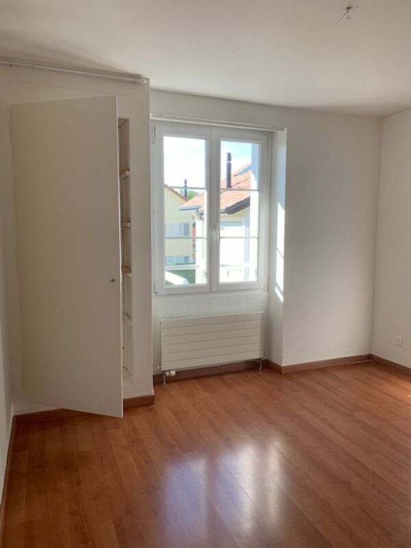Helles, leeres Zimmer mit Fenster und Heizkörper