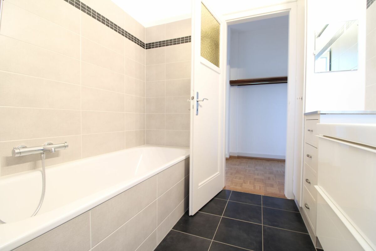 Badezimmer mit Badewanne und begehbarer Sicht in den Ankleidebereich