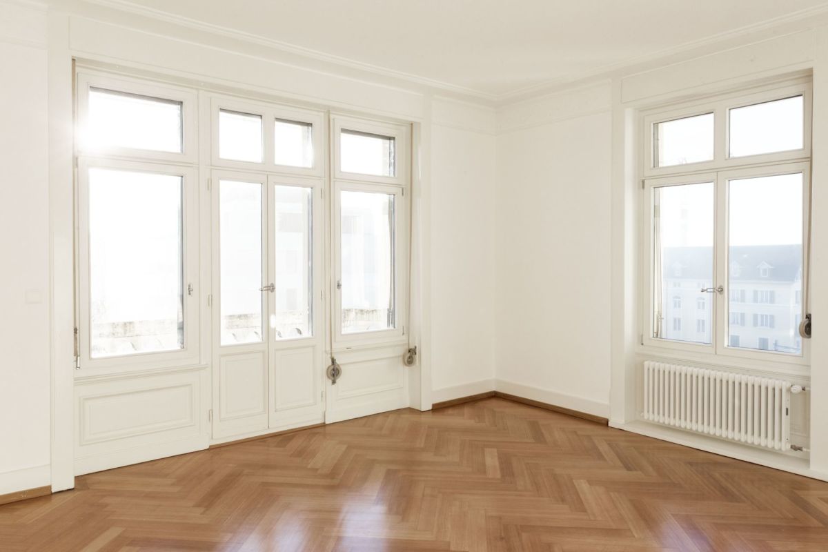 Heller leerer Altbau-Raum mit großen Fenstern
