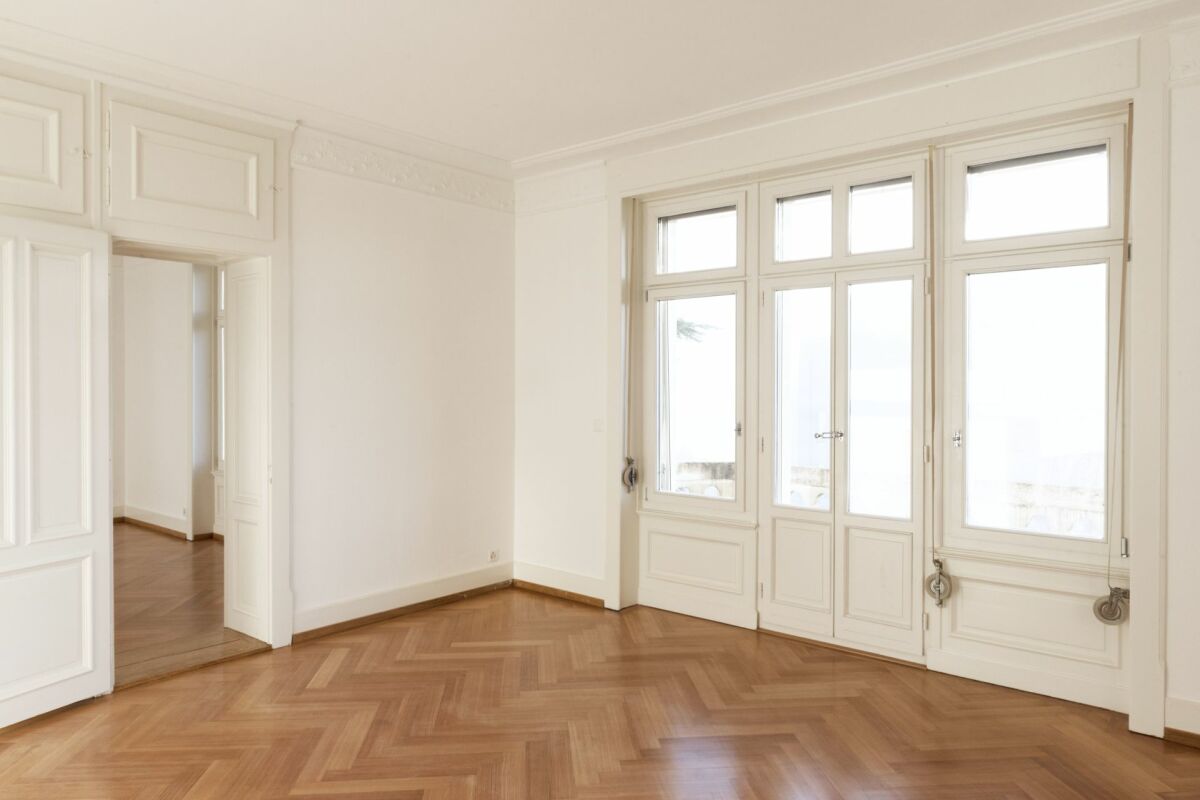 Heller Altbau-Raum mit hohen Fenstern und Fischgrätparkett