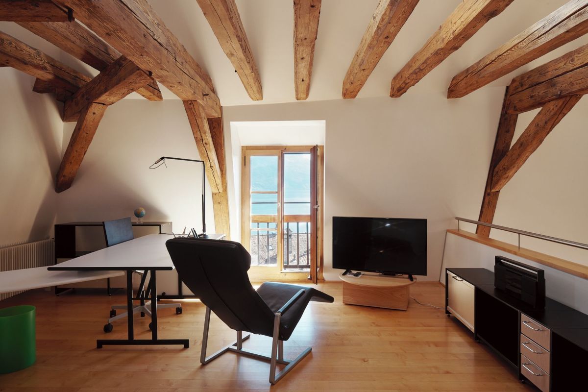 Dachgeschossraum mit sichtbaren Holzbalken und Meerblick