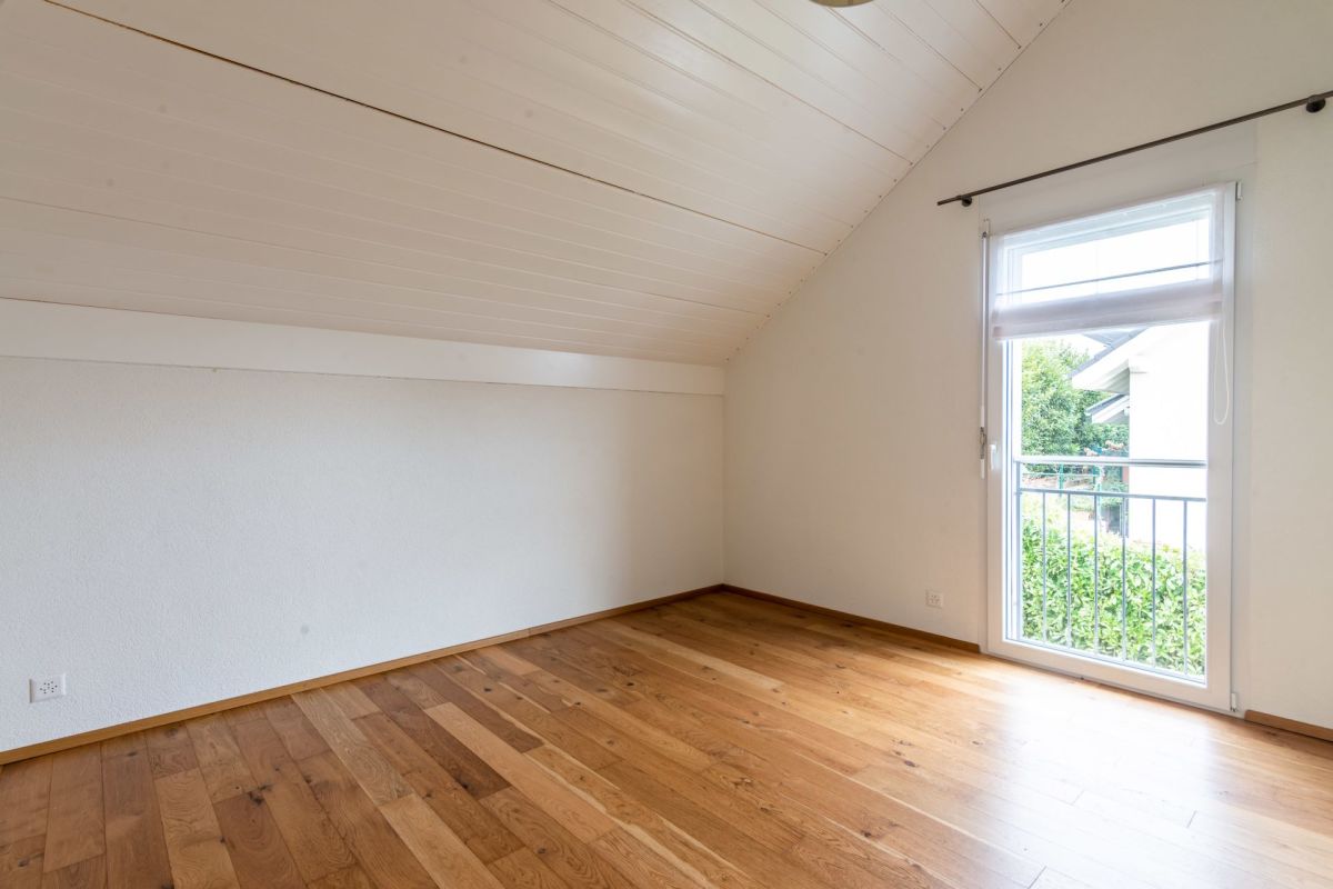 Leeres Dachgeschosszimmer mit Balkon- bzw. Fenstertür
