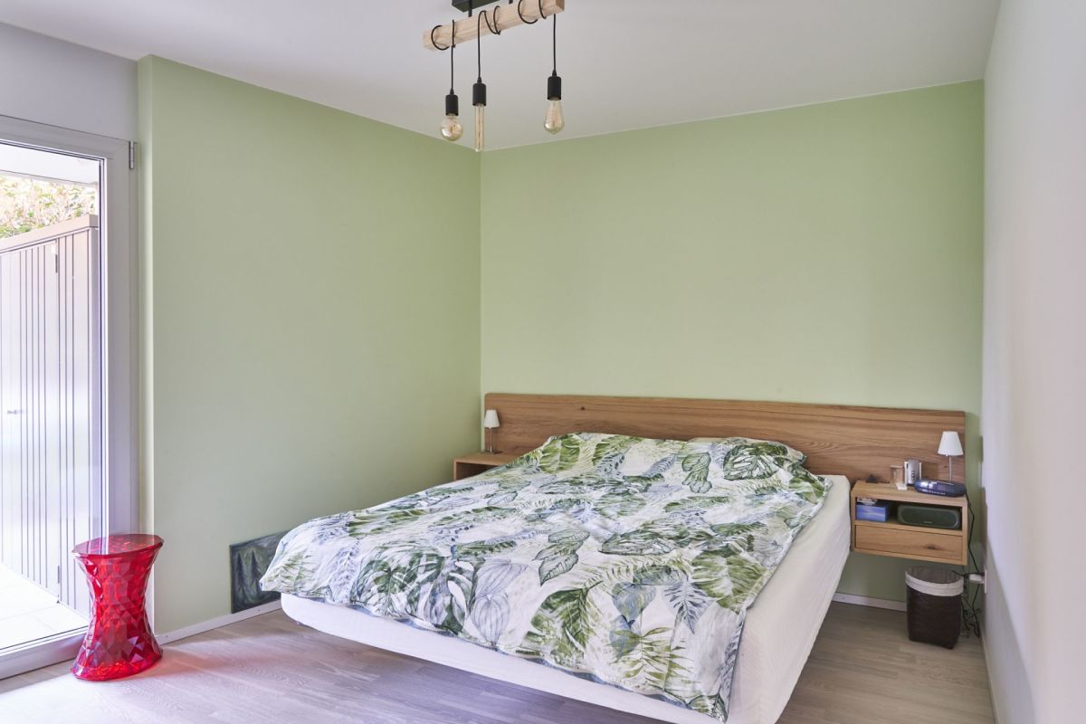 Schlafzimmer mit grün gestrichenen Wänden und Holzbett