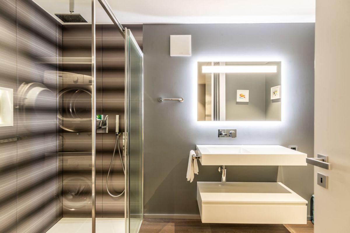 Modernes Badezimmer mit begehbarer Dusche und beleuchtetem Spiegel