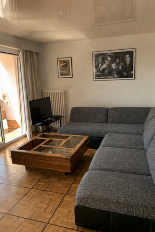 Wohnzimmer mit großer Eckcouch und Balkonzugang