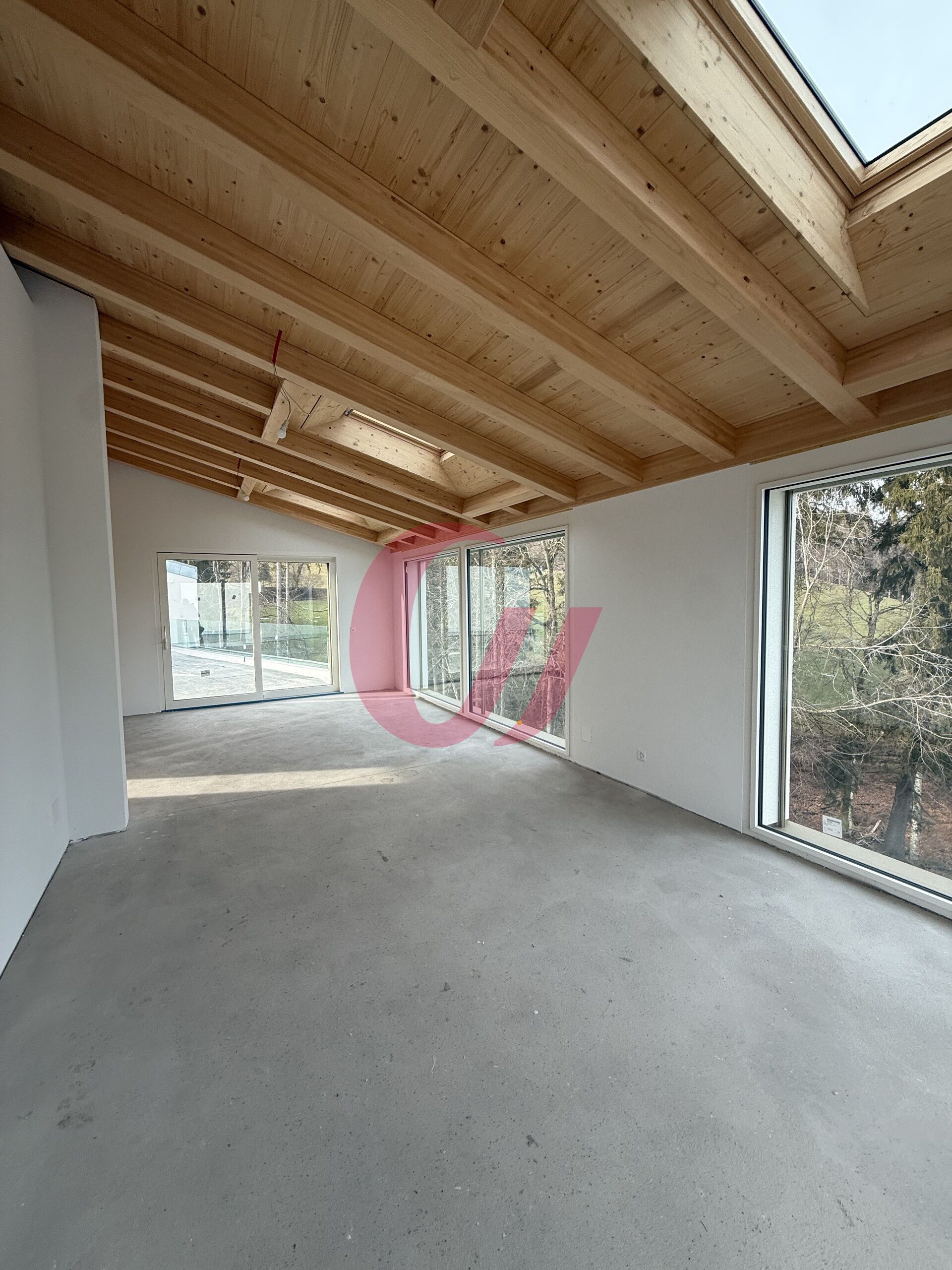 Heller, leerer Innenraum mit Holzdecke und großen Fenstern