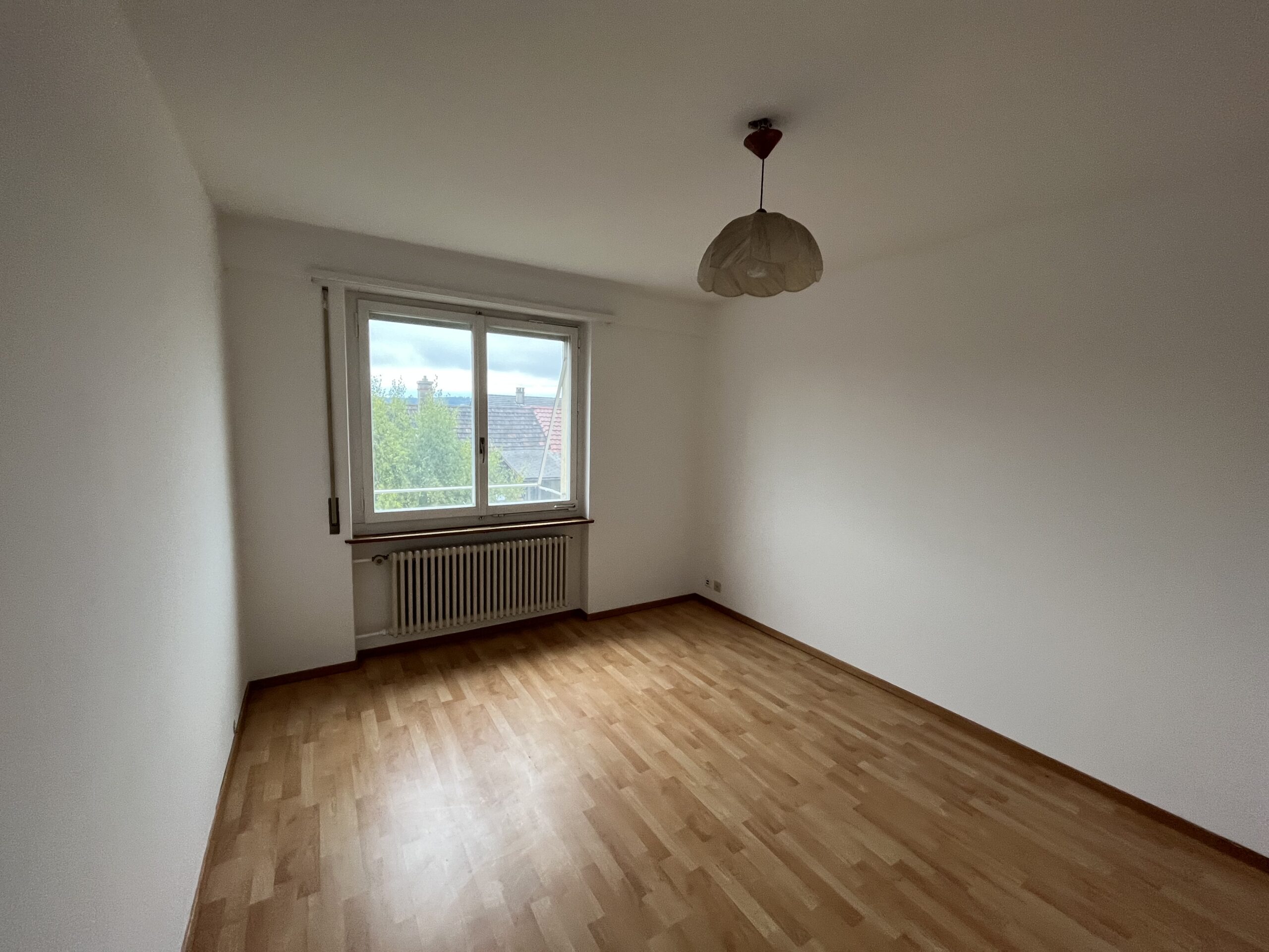 Leerer Wohnraum mit Fenster und Heizkörper