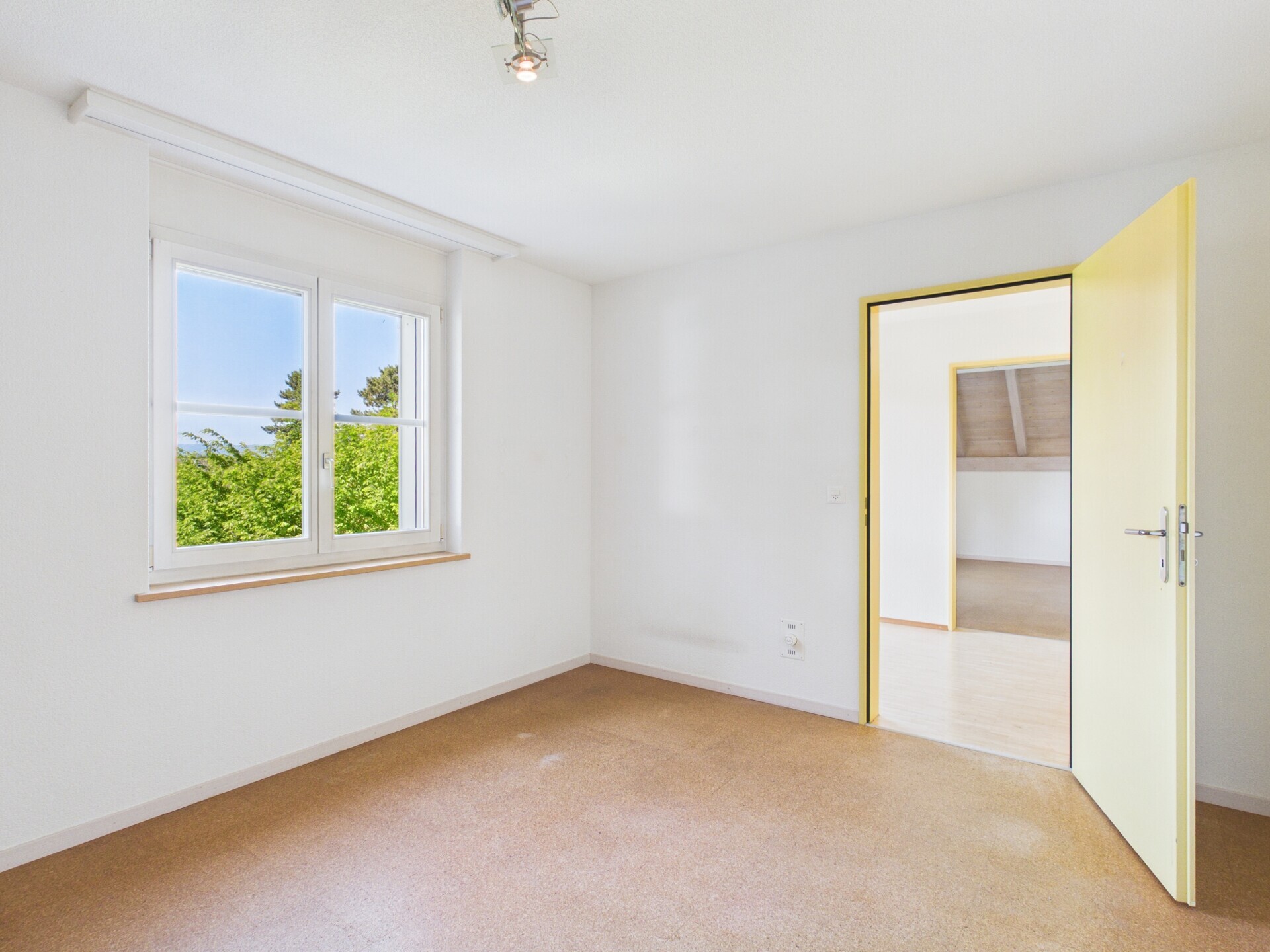 Helles, leeres Zimmer mit Fenster und offener Tür