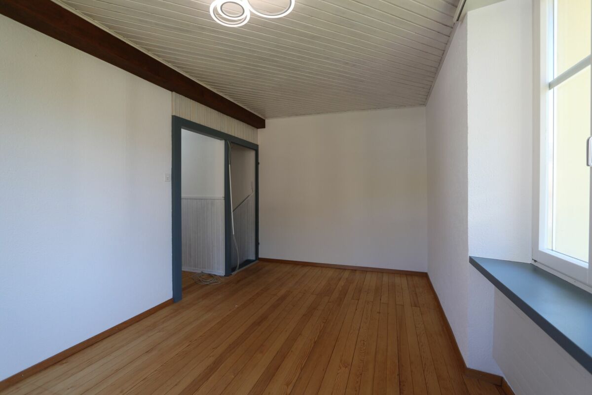 Heller leerer Raum mit Holzboden und schräger Holzdecke