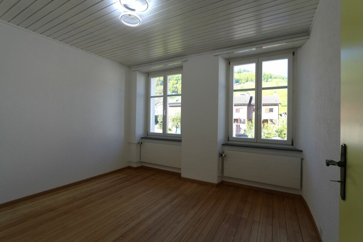 Heller leerer Raum mit Parkett und zwei Fenstern