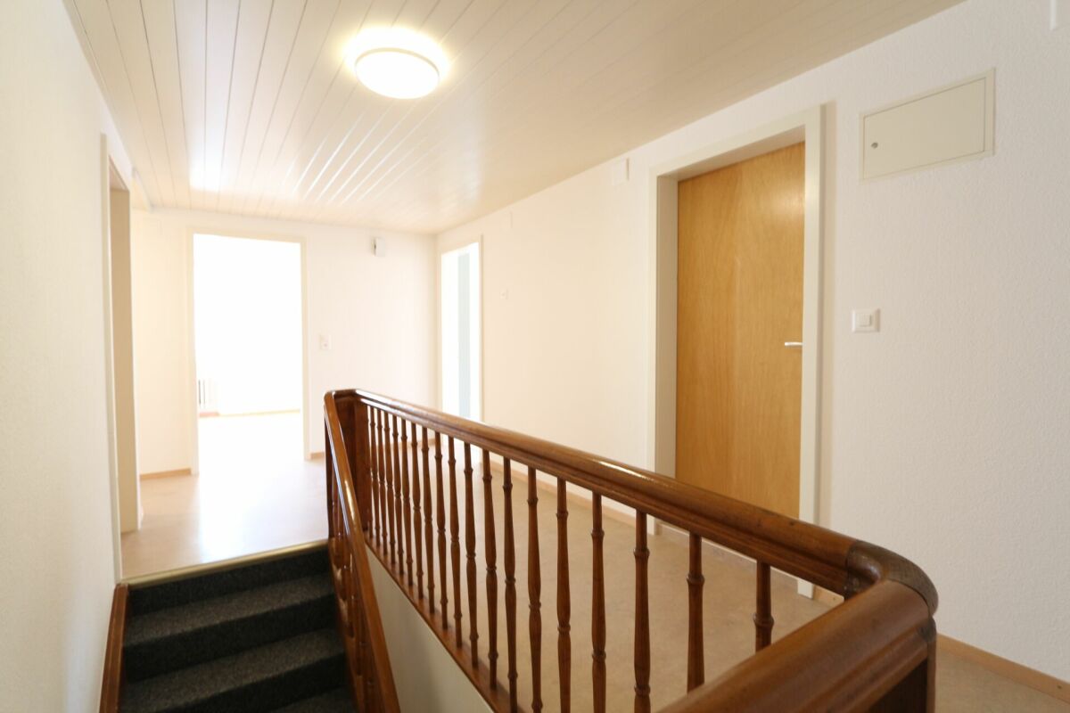 Heller Flur mit Treppenpodest und Holzgeländer