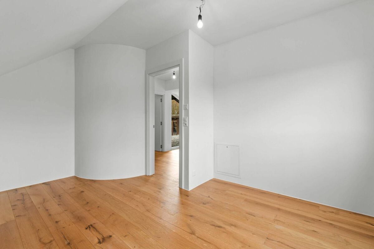 Heller leerer Raum mit Holzboden und weiß gestrichenen Wänden