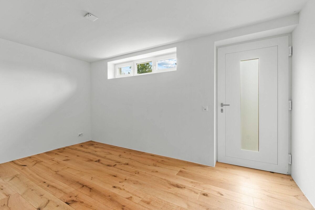 Helles leeres Zimmer mit Holzfußboden und schmalem Oberlicht