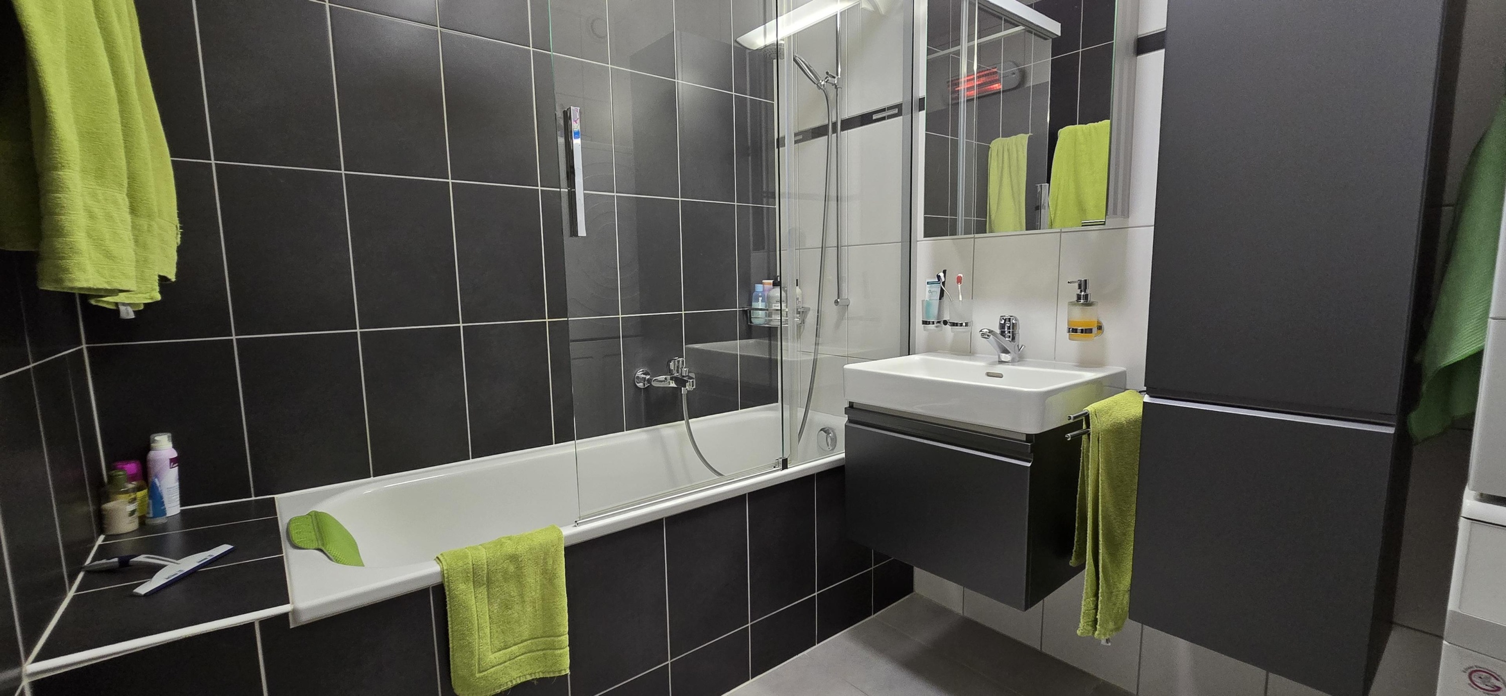 Modernes Badezimmer mit dunklen Fliesen und Badewanne