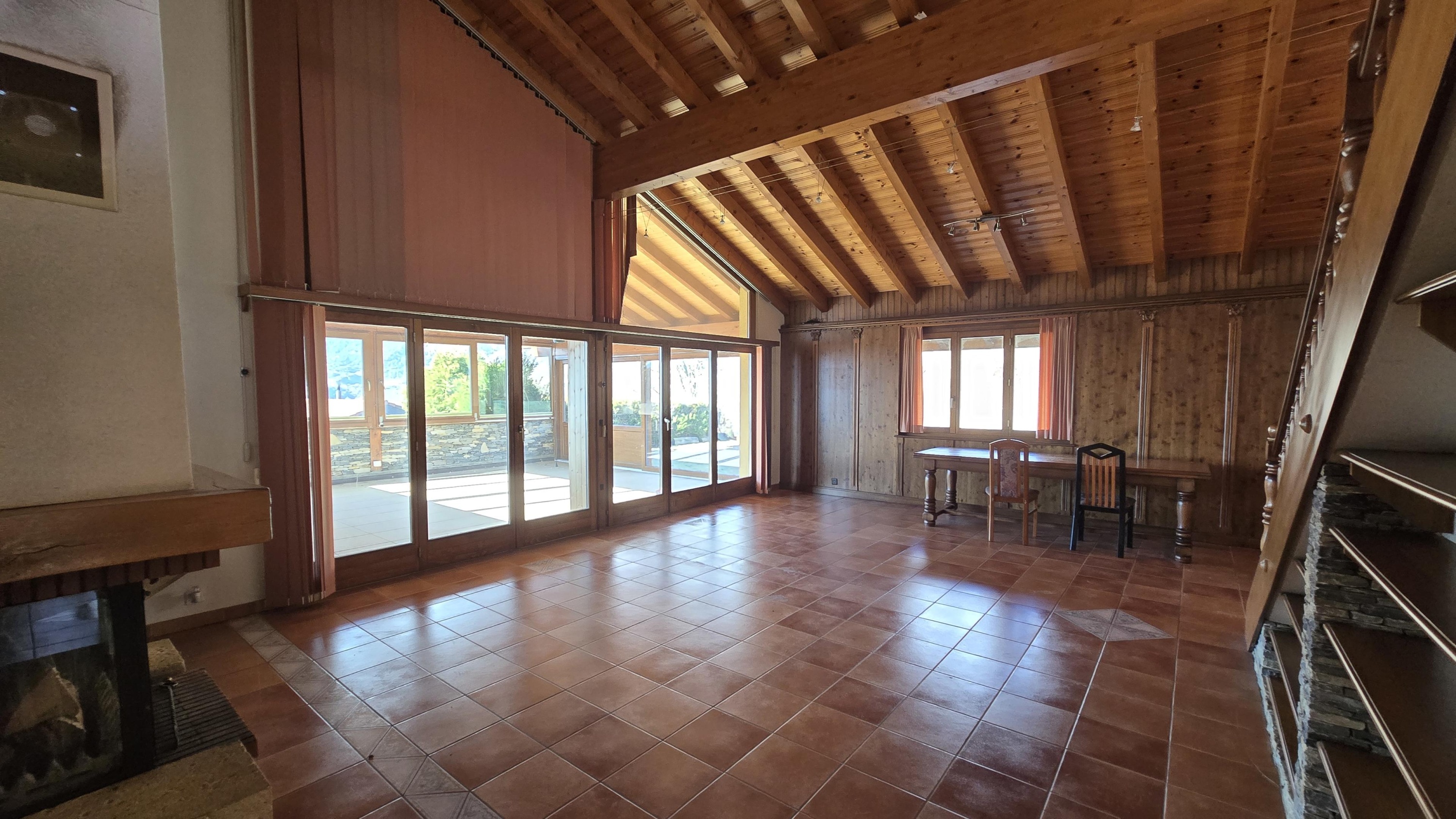Großer Wohnraum mit Holzdecke und Terrakottafliesen